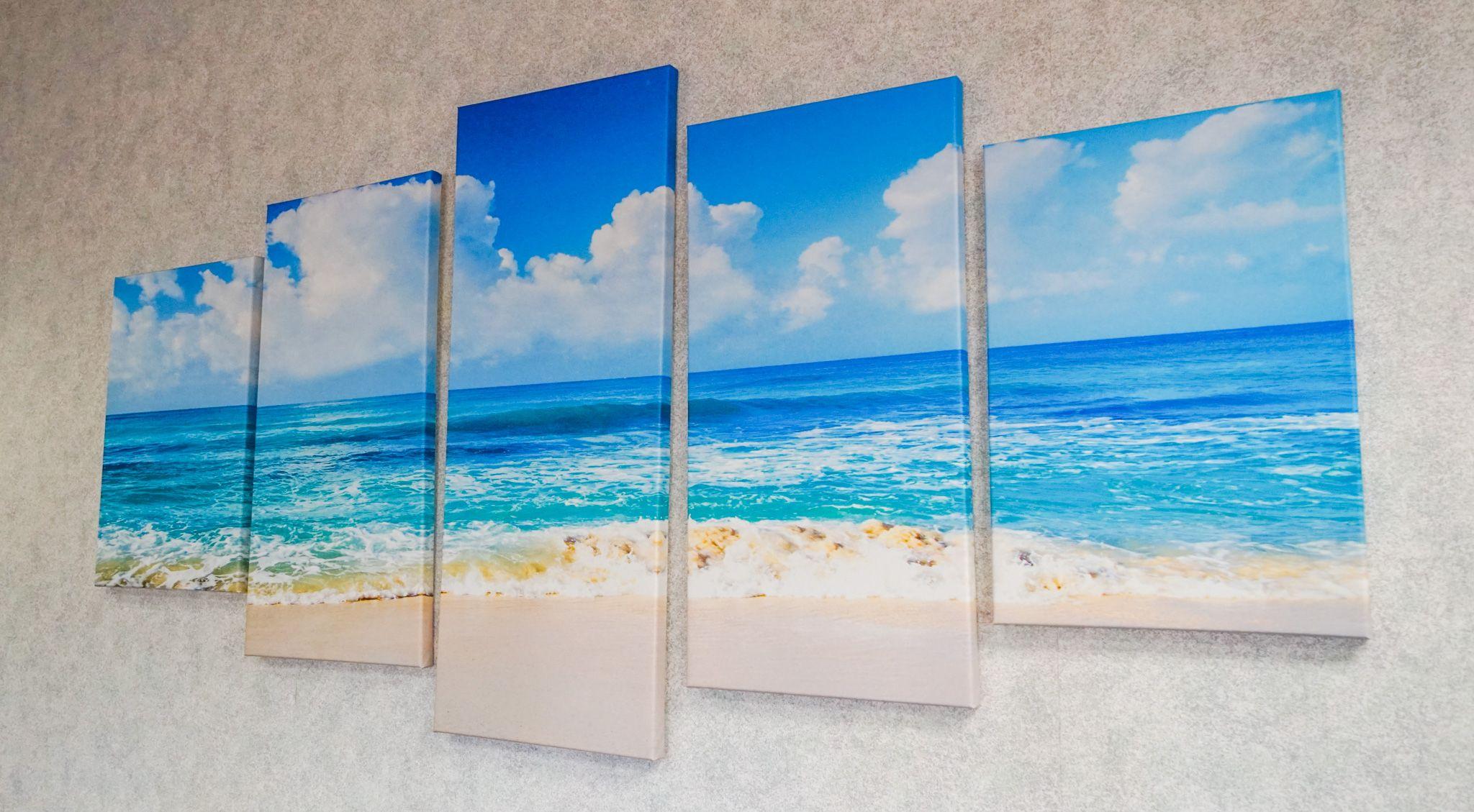 a painting of a beach and ocean is hanging on a wall .