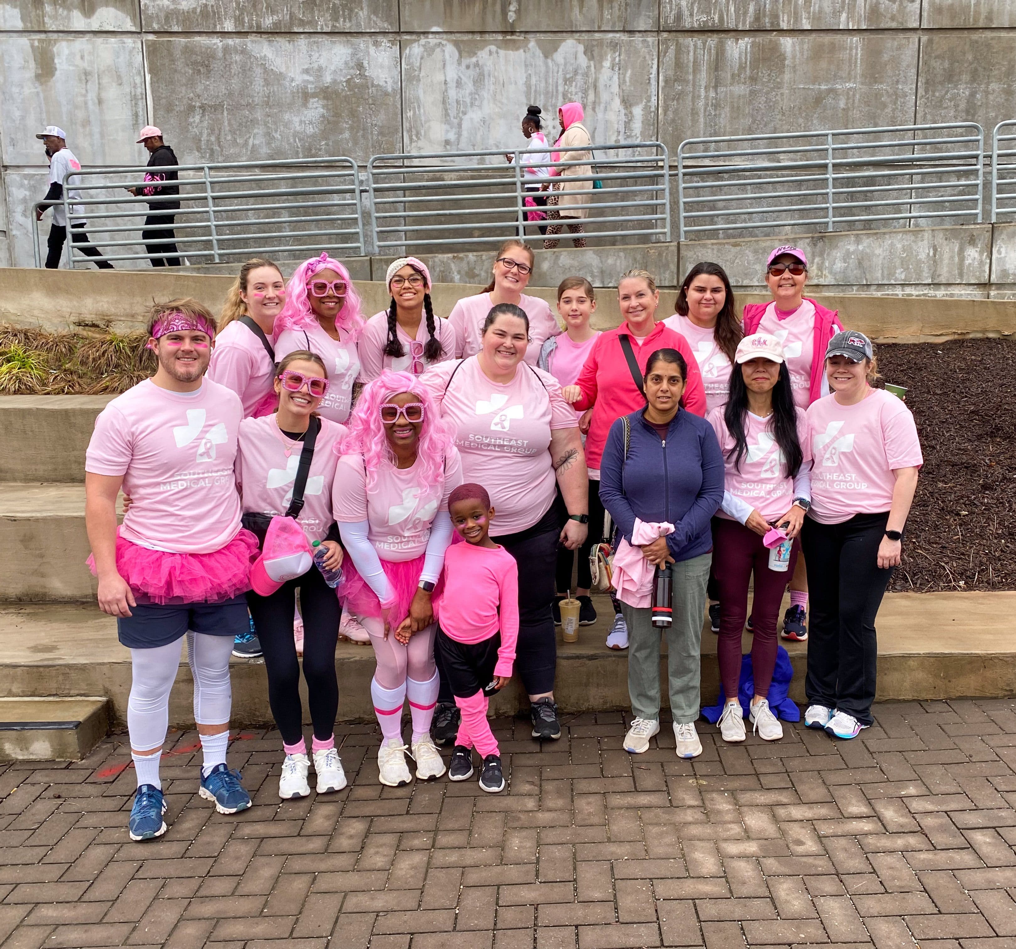 a group of people wearing pink shirts and tutus are posing for a picture .