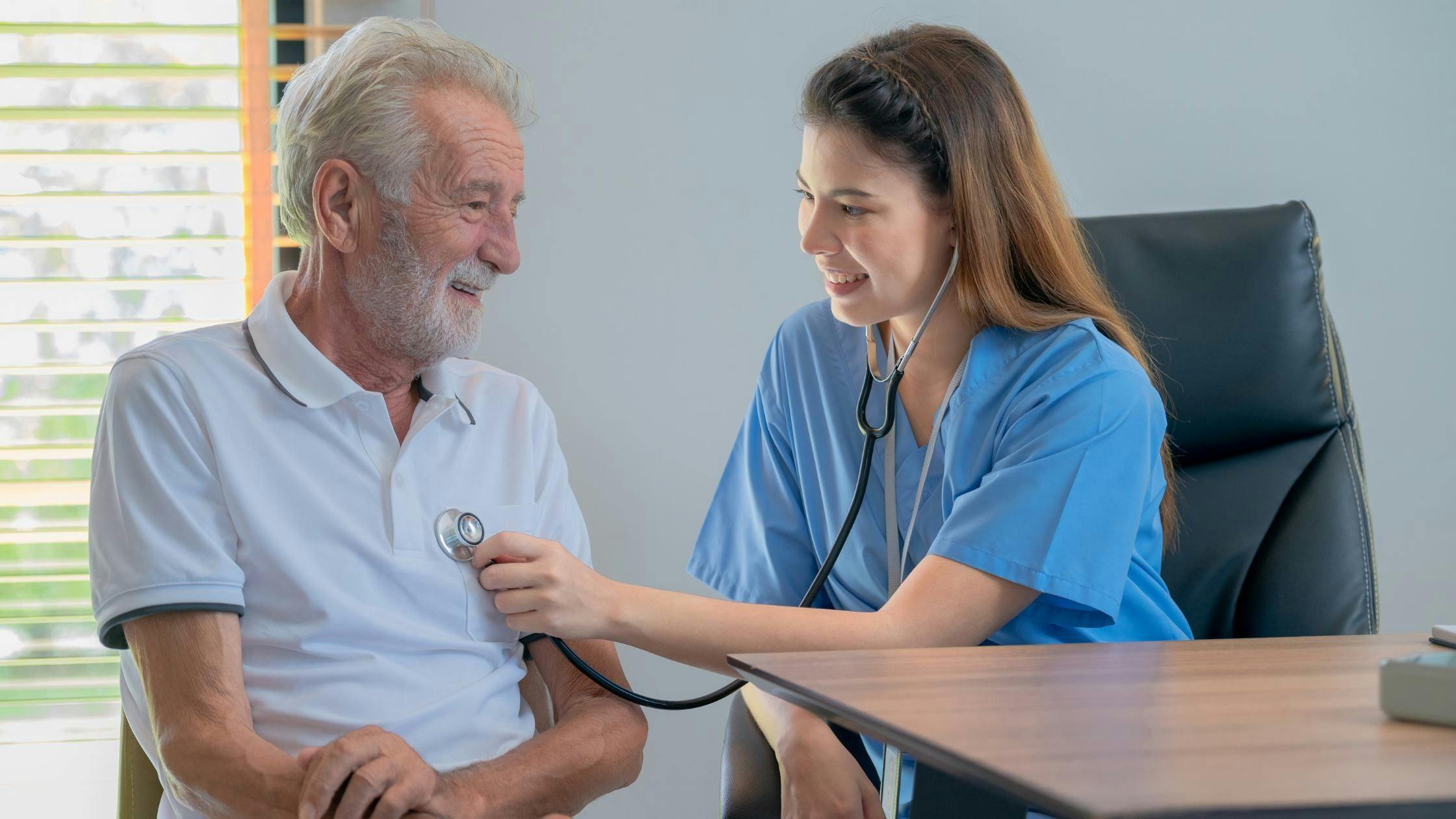 a nurse is listening to an older man 's heartbeat with a stethoscope .