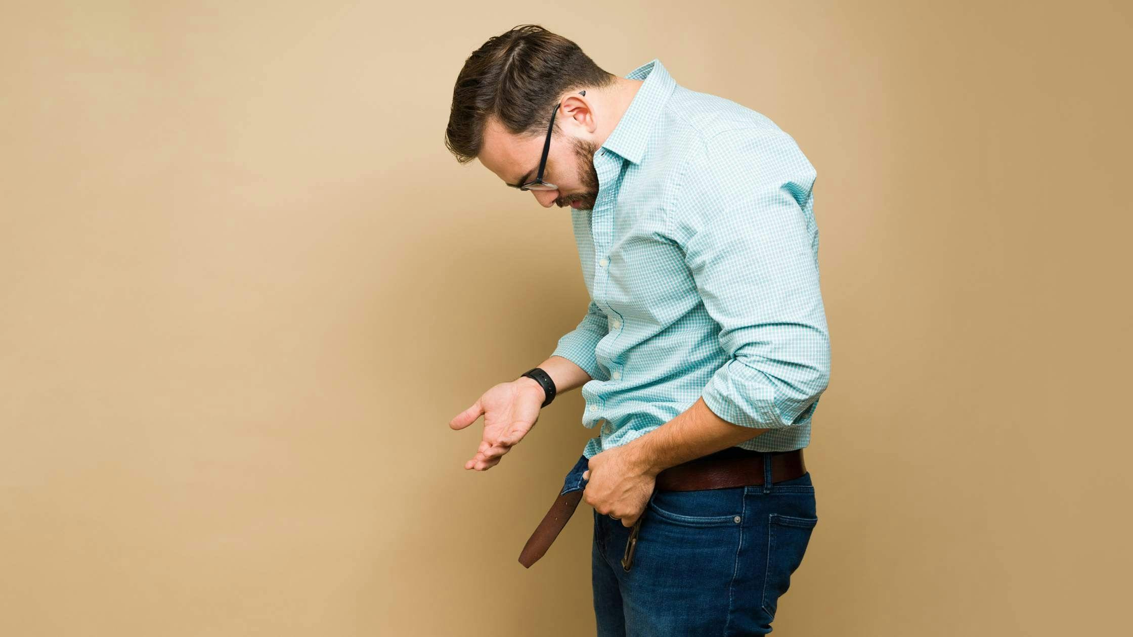 a man in a blue shirt is taking off his belt .
