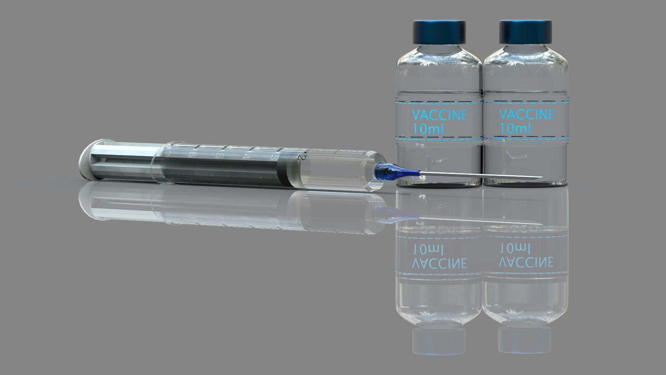 a syringe is sitting next to two bottles of vaccine .