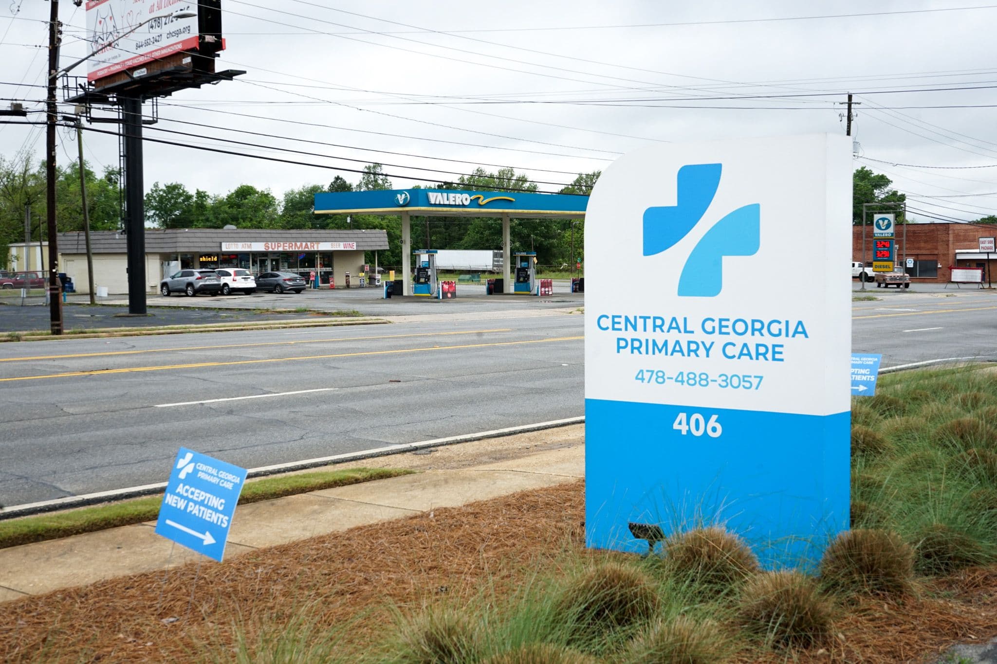 a blue and white sign for central georgia primary care is in front of a gas station .