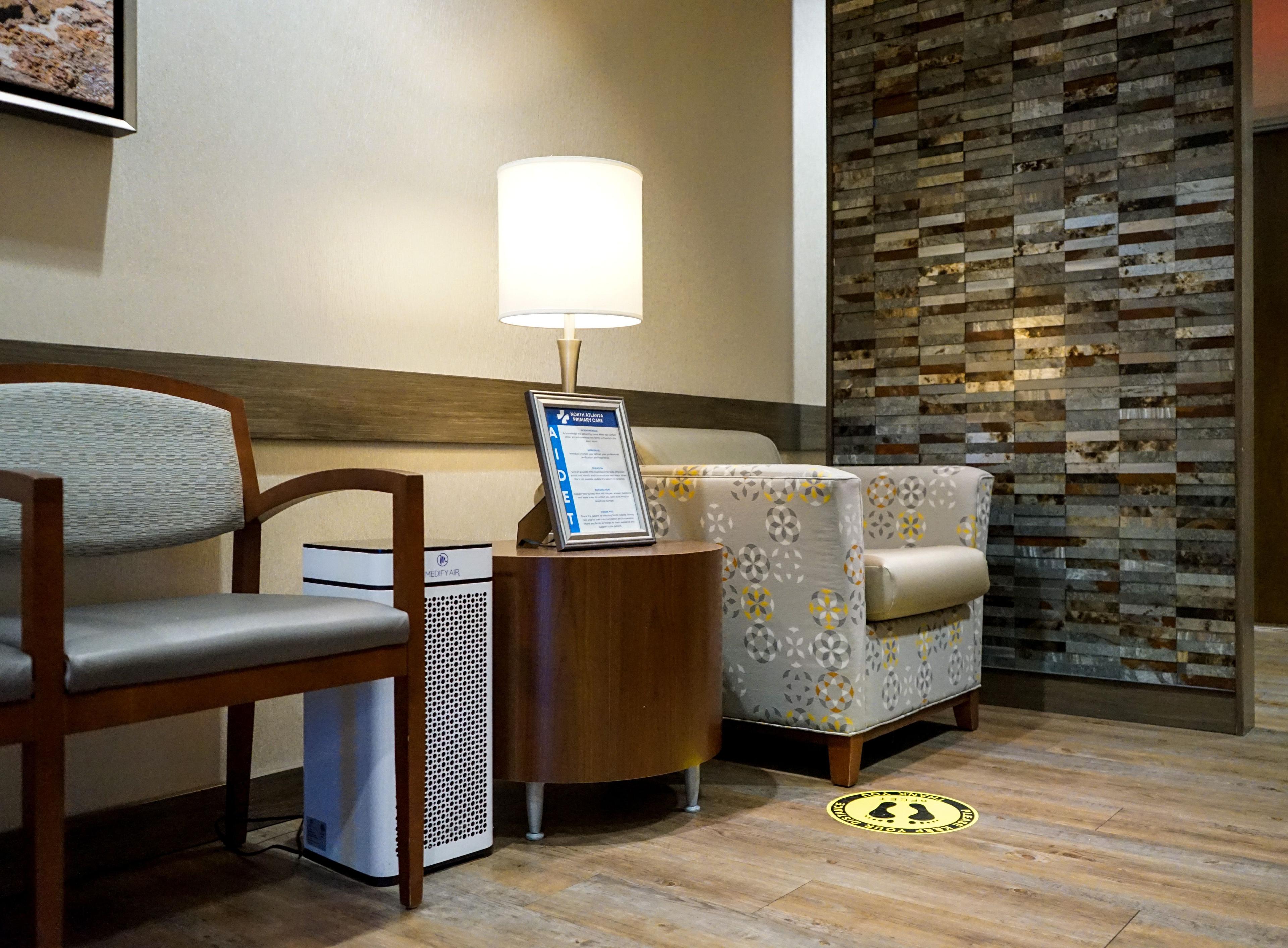 a waiting room with chairs , a table , a lamp and a sign .