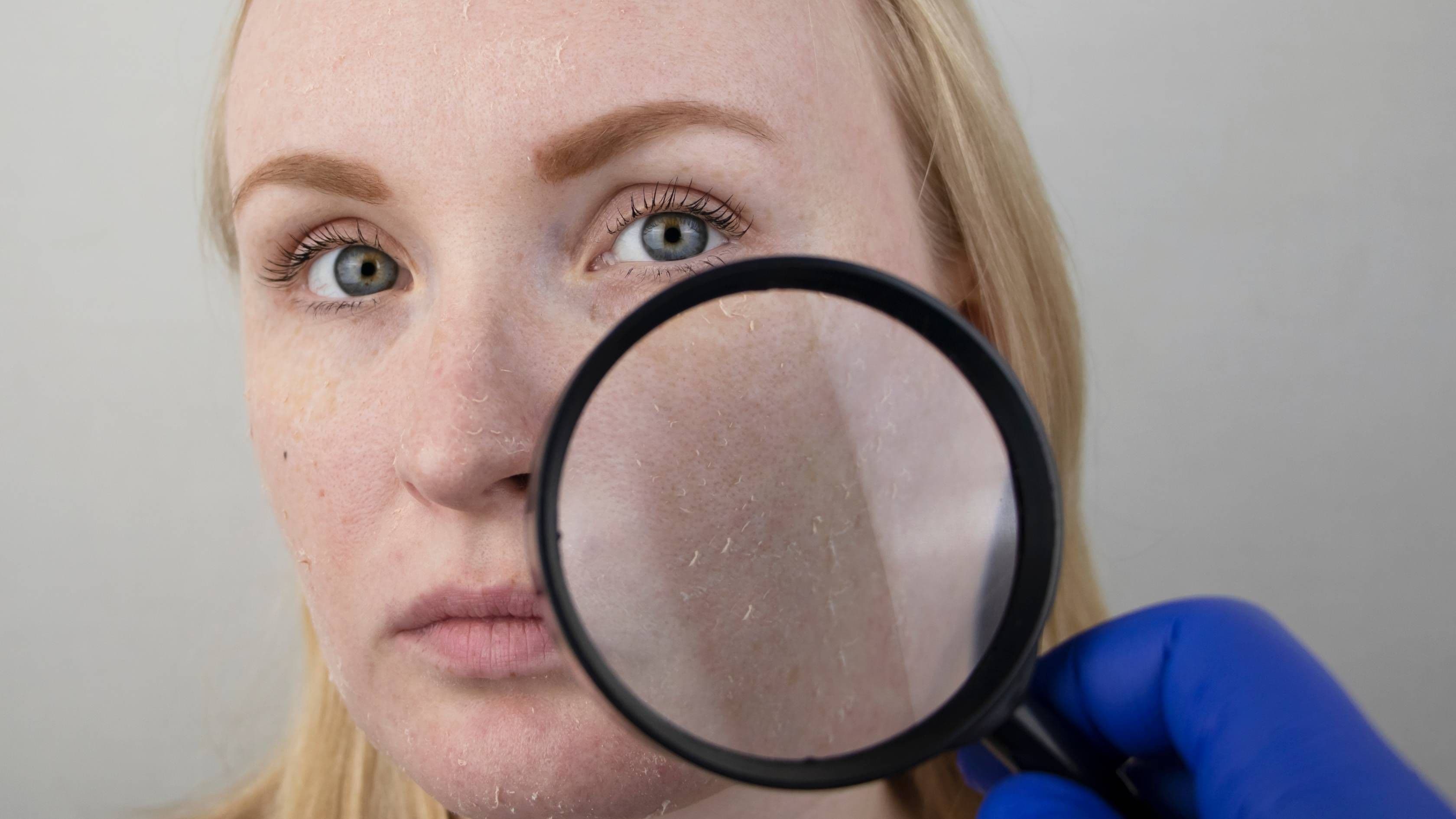 a woman is looking at her face through a magnifying glass .