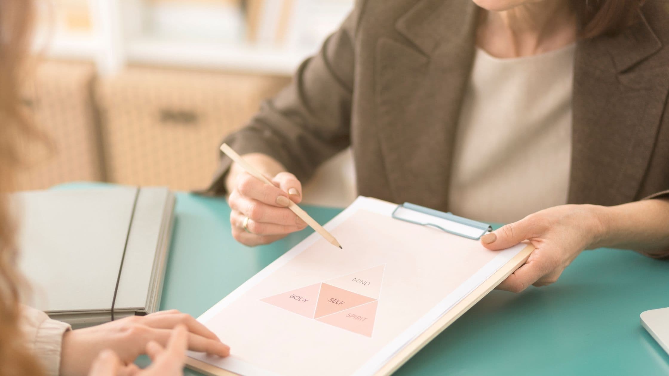 a woman is pointing at a graph on a clipboard while another woman looks on .