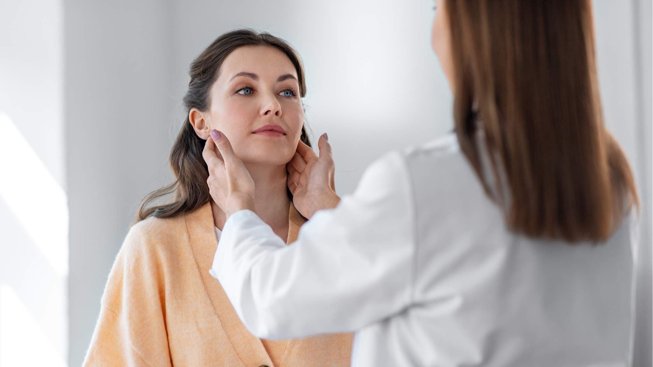 a doctor is examining a woman 's face in front of a mirror .