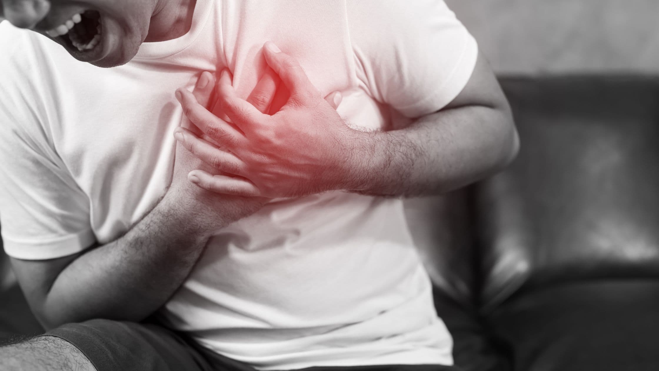 a man is sitting on a couch holding his chest in pain .