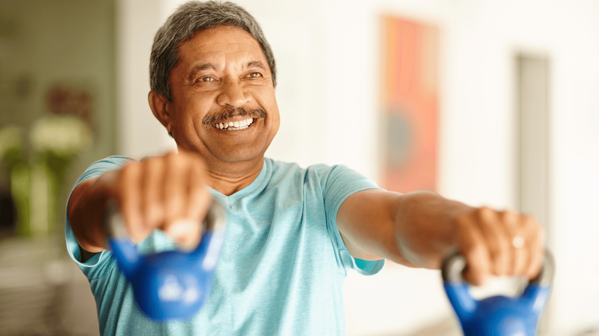 a man in a blue shirt is smiling while holding two blue weights