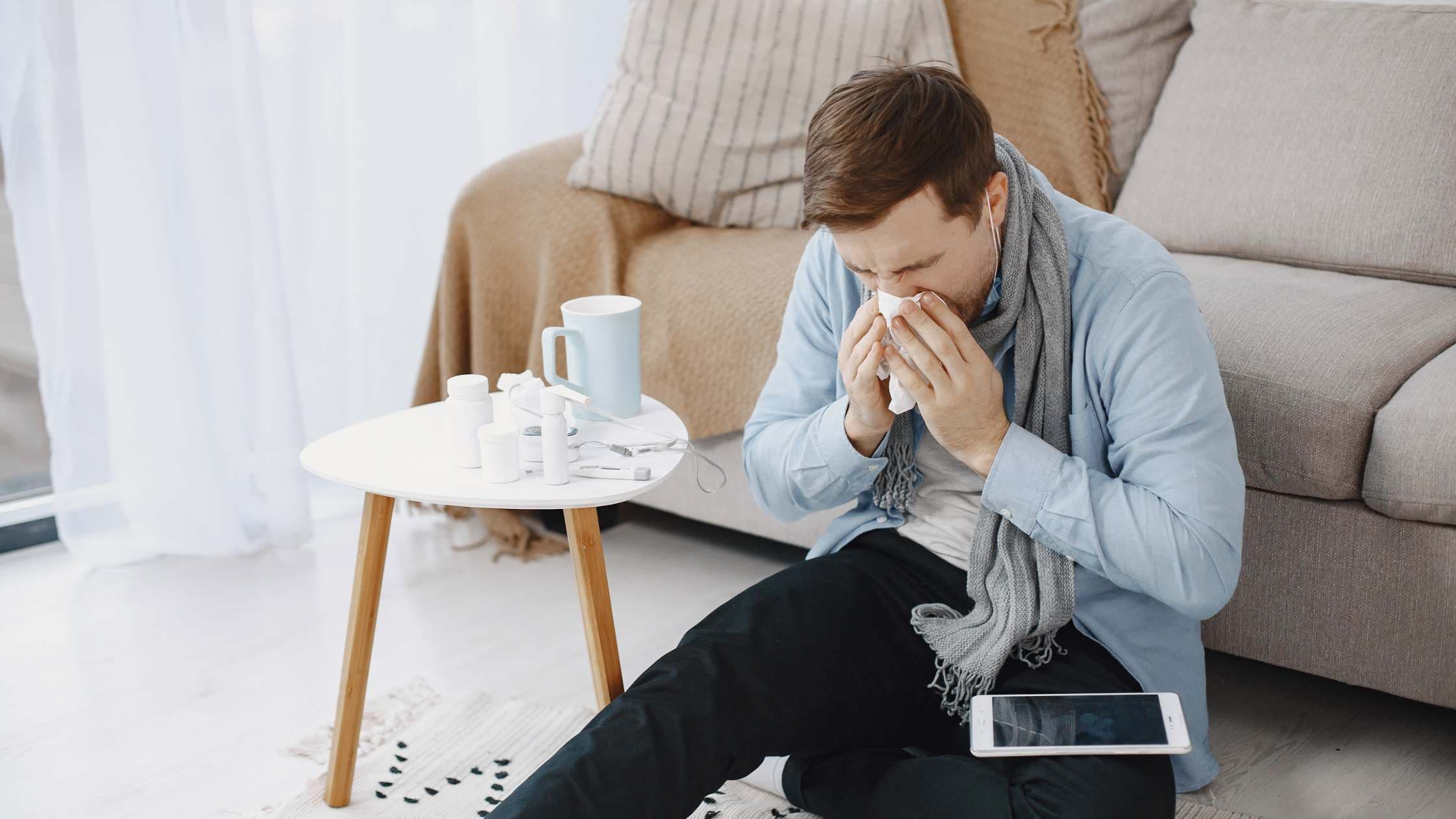 a man is sitting on the floor blowing his nose in a napkin .