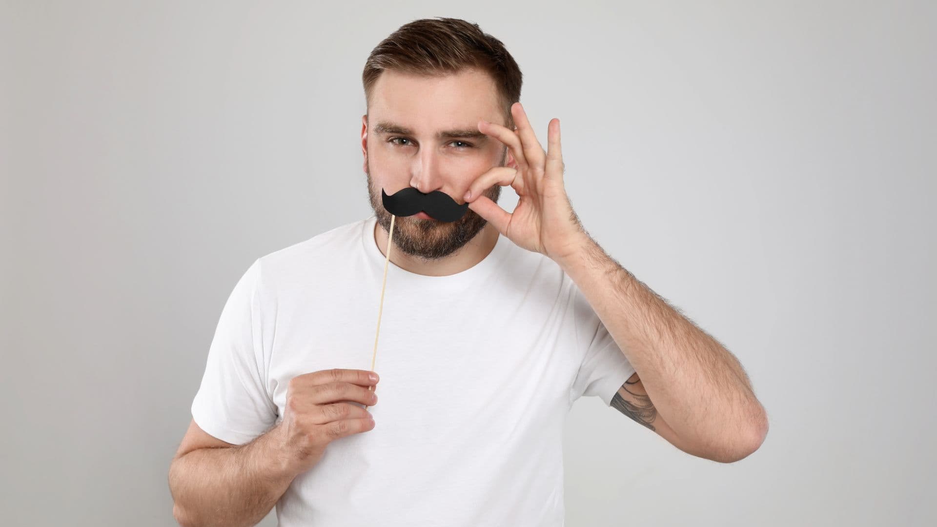 a man is holding a fake mustache in front of his face .