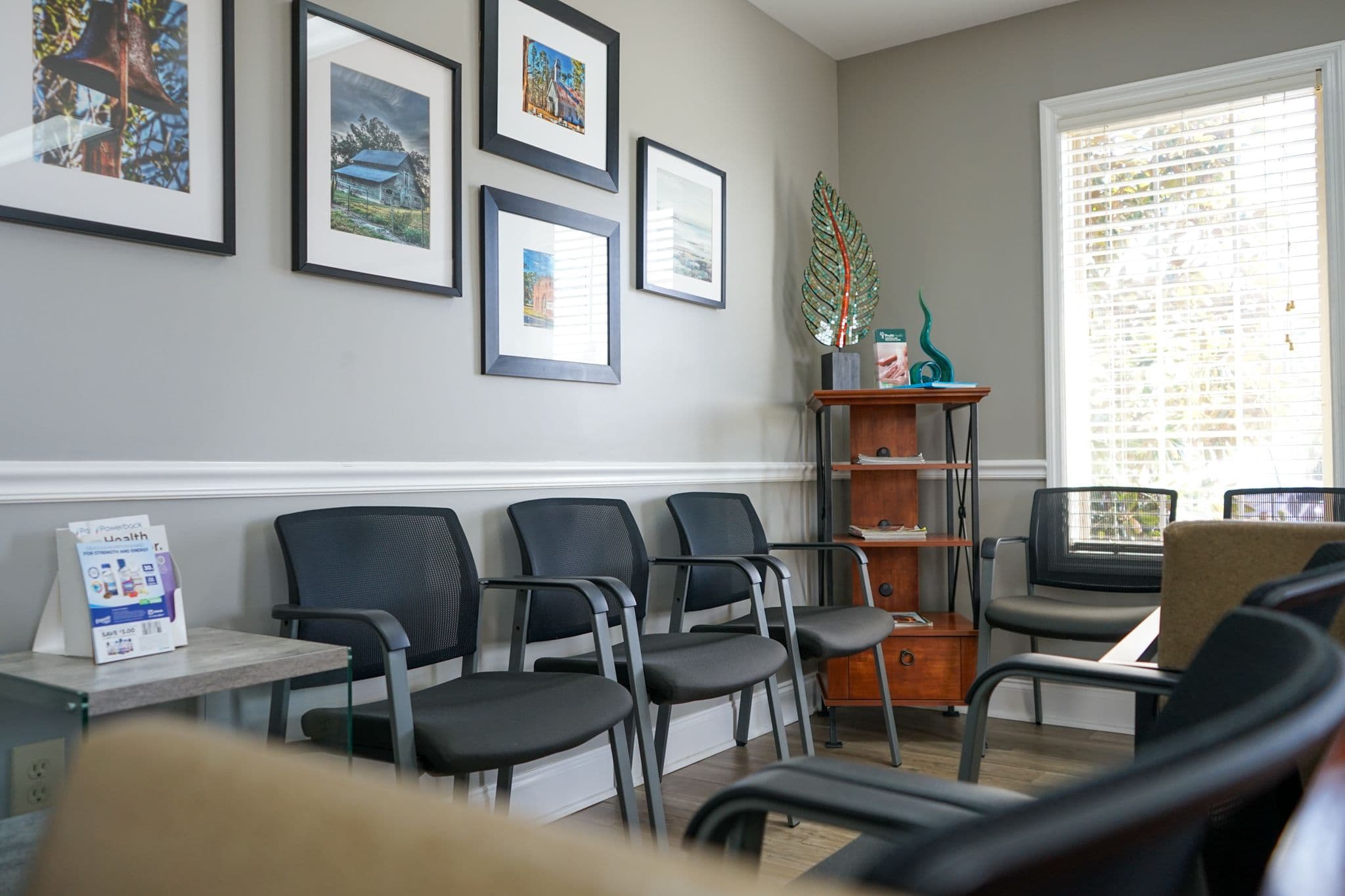 a row of chairs in a waiting room with pictures on the wall at South Georgia Internal Medicine at Swainsboro . 