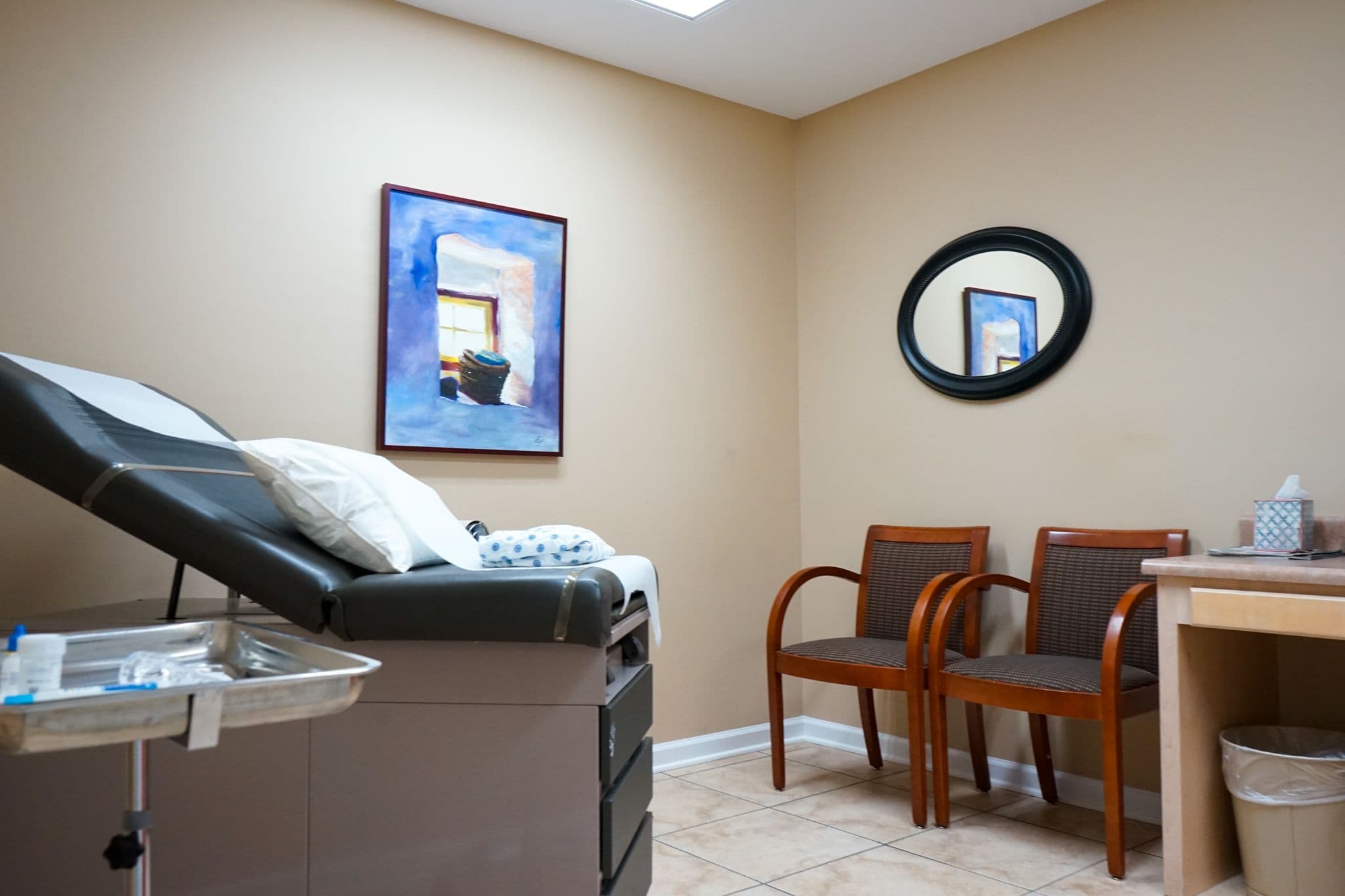 an exam room with a couch , chairs , and a mirror at South Georgia Internal Medicine at Swainsboro . 