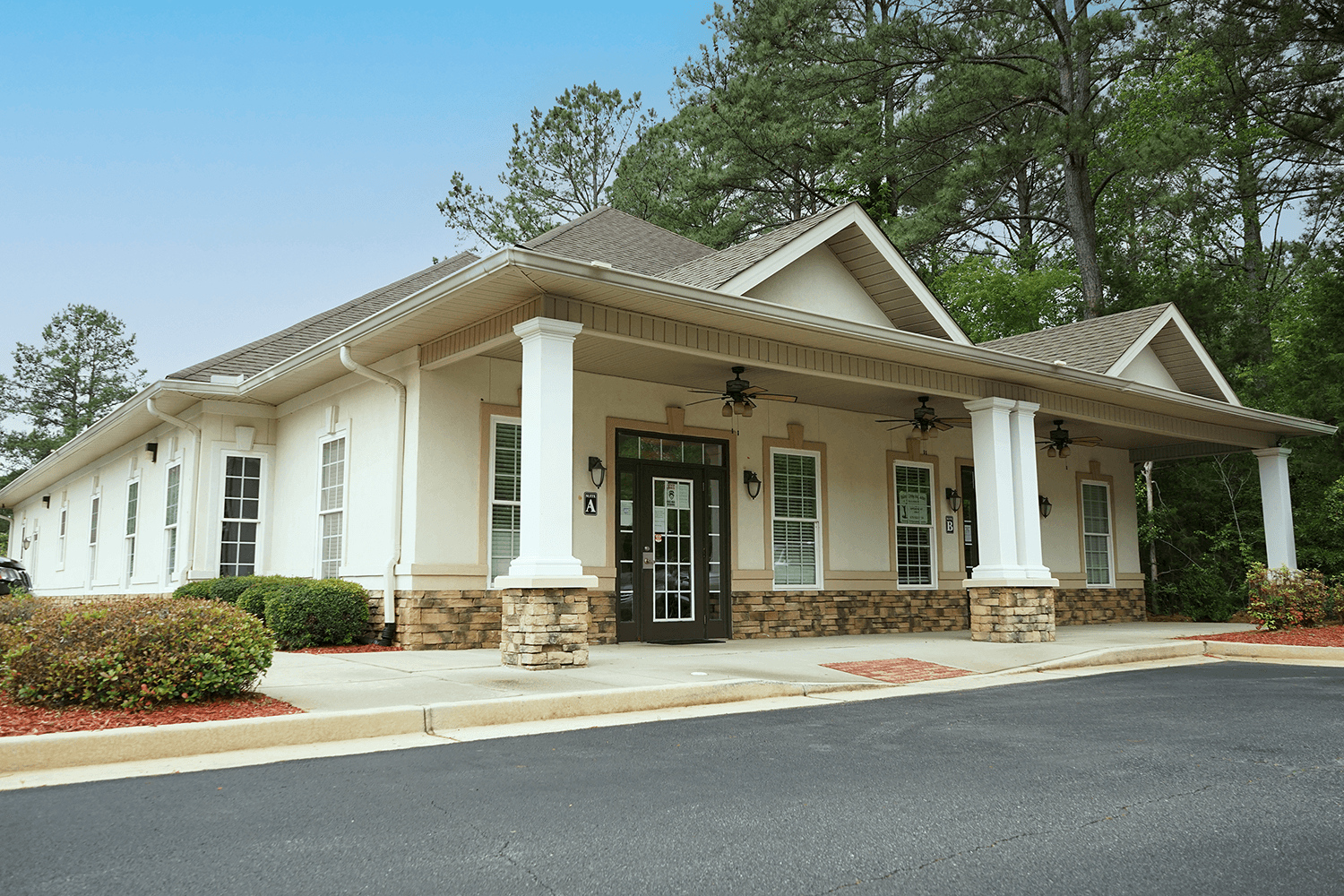 a white building with a covered porch and a black door