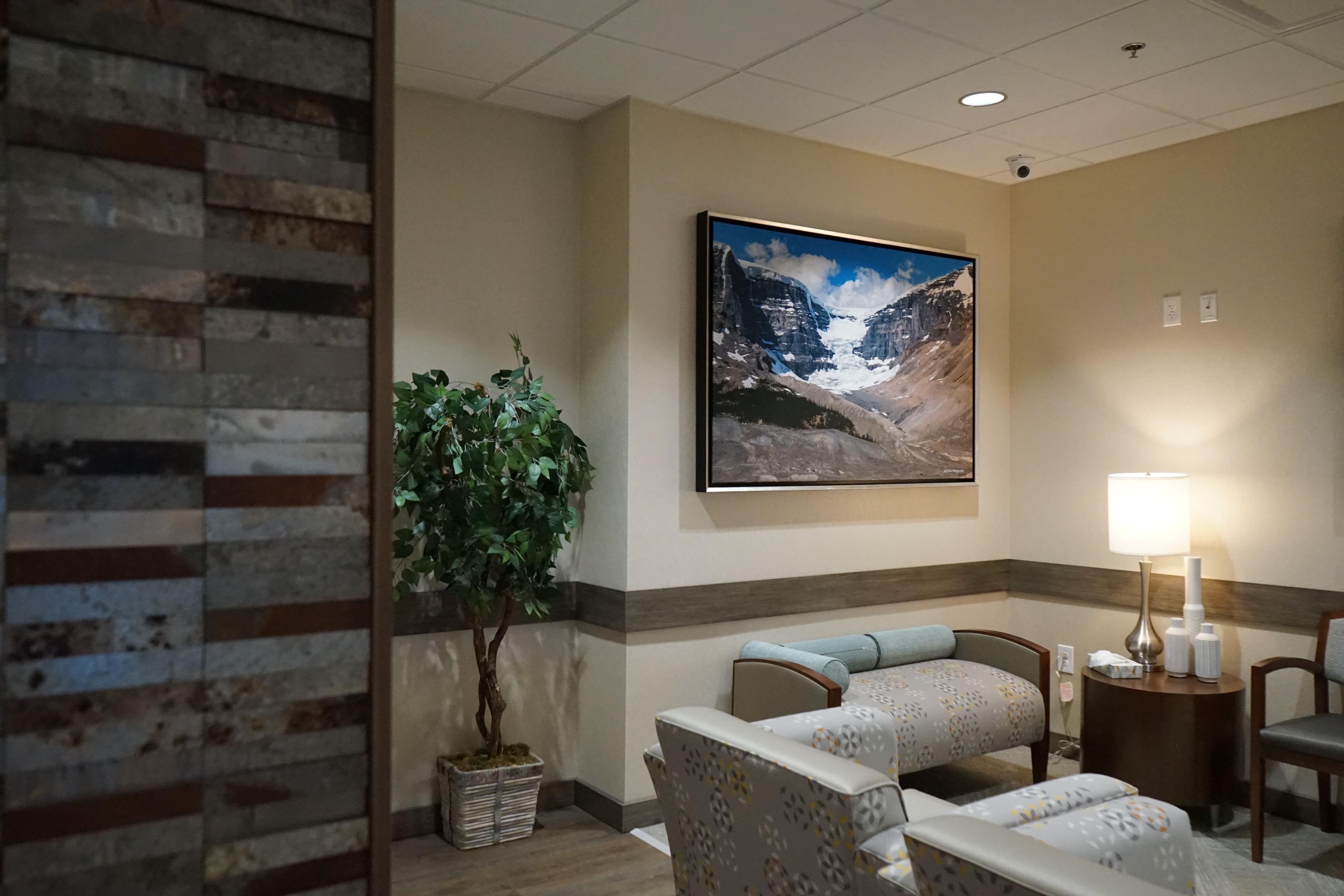 a waiting room with chairs and a painting on the wall .