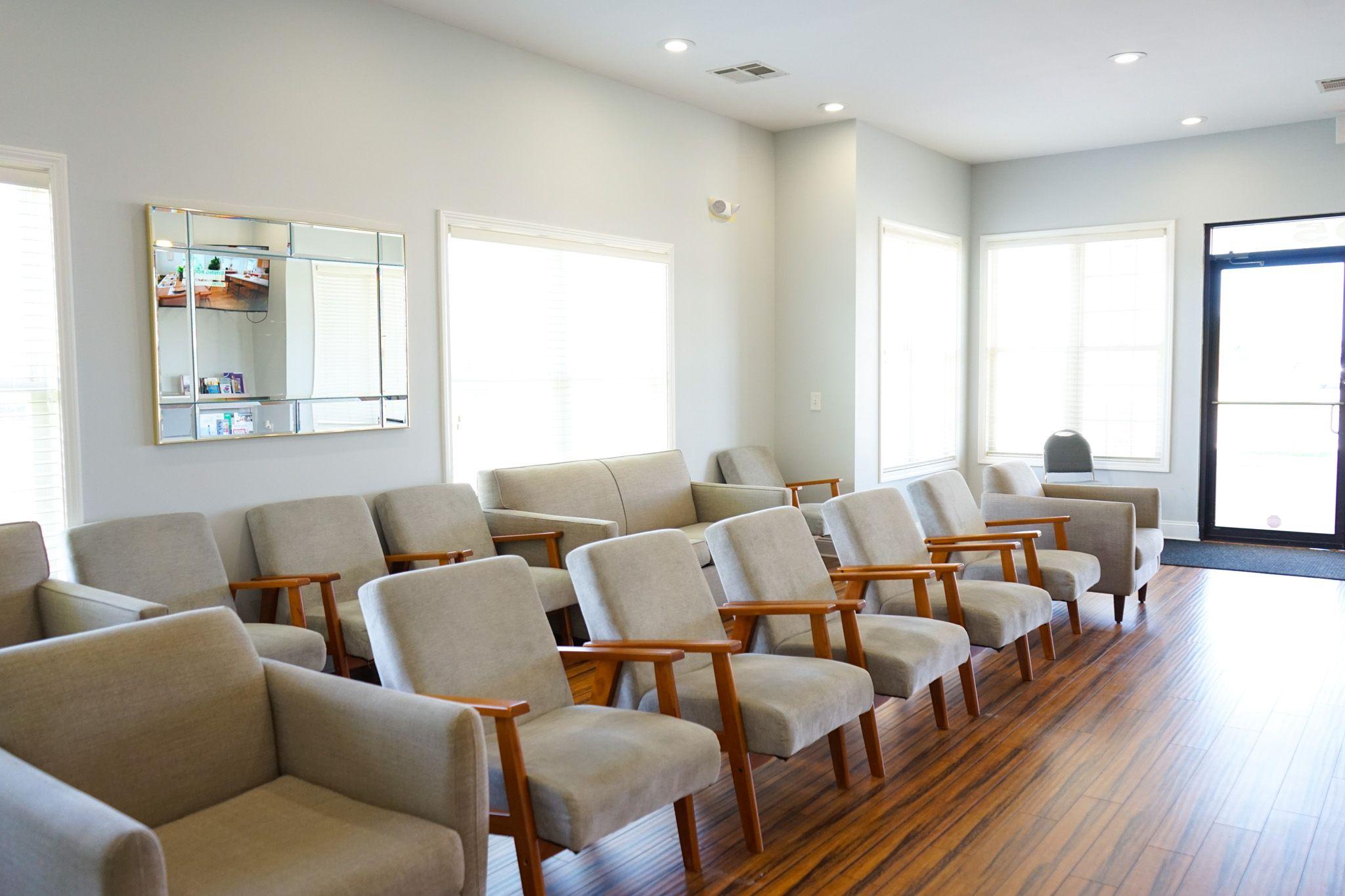 a waiting room with a lot of chairs and a mirror .