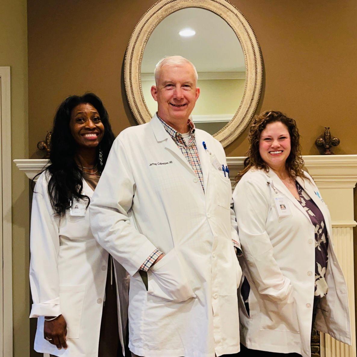 a group of doctors are posing for a picture in front of a mirror .