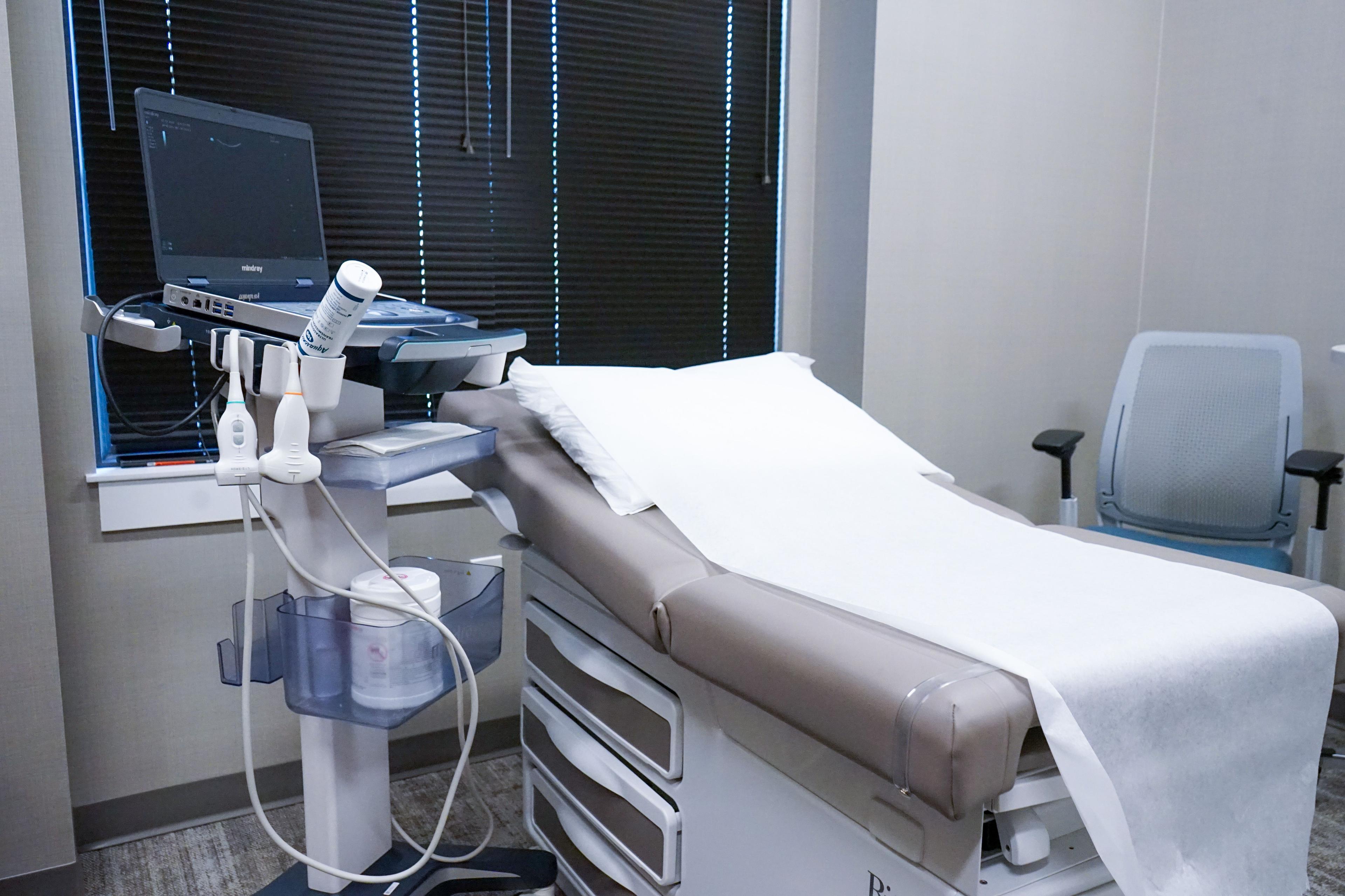 a doctor 's office with a bed and an ultrasound machine .