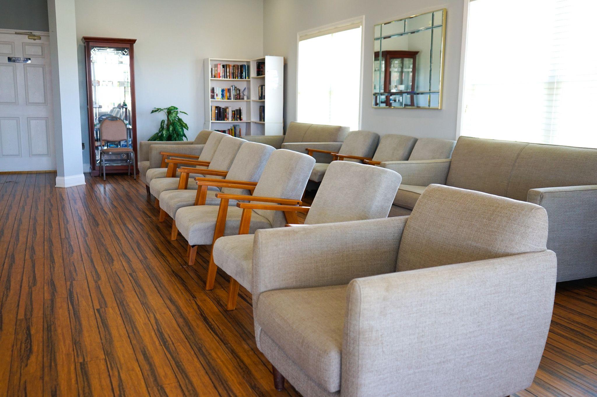 a row of chairs and couches in a living room with wooden floors .