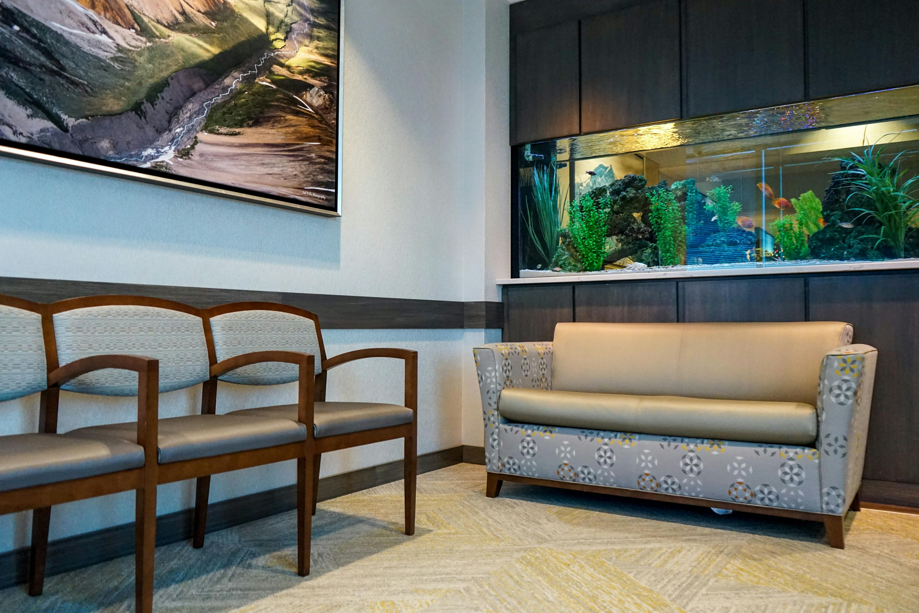 a waiting room with a couch , chairs and an aquarium .