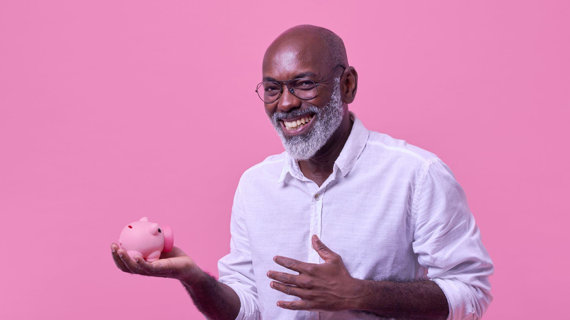 an older man is holding a pink piggy bank in his hand .