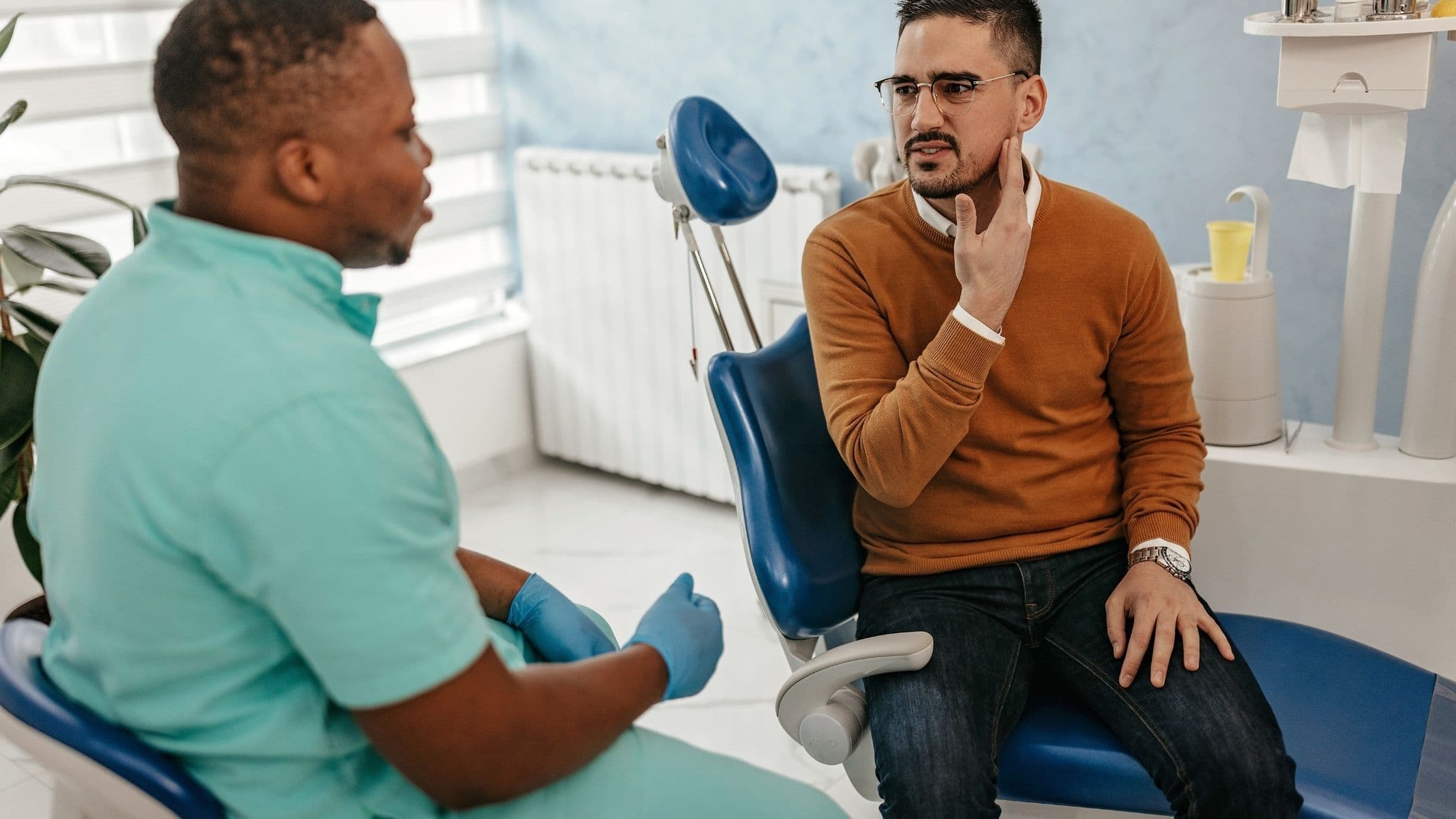 a man is sitting in a dental chair talking to a dentist .