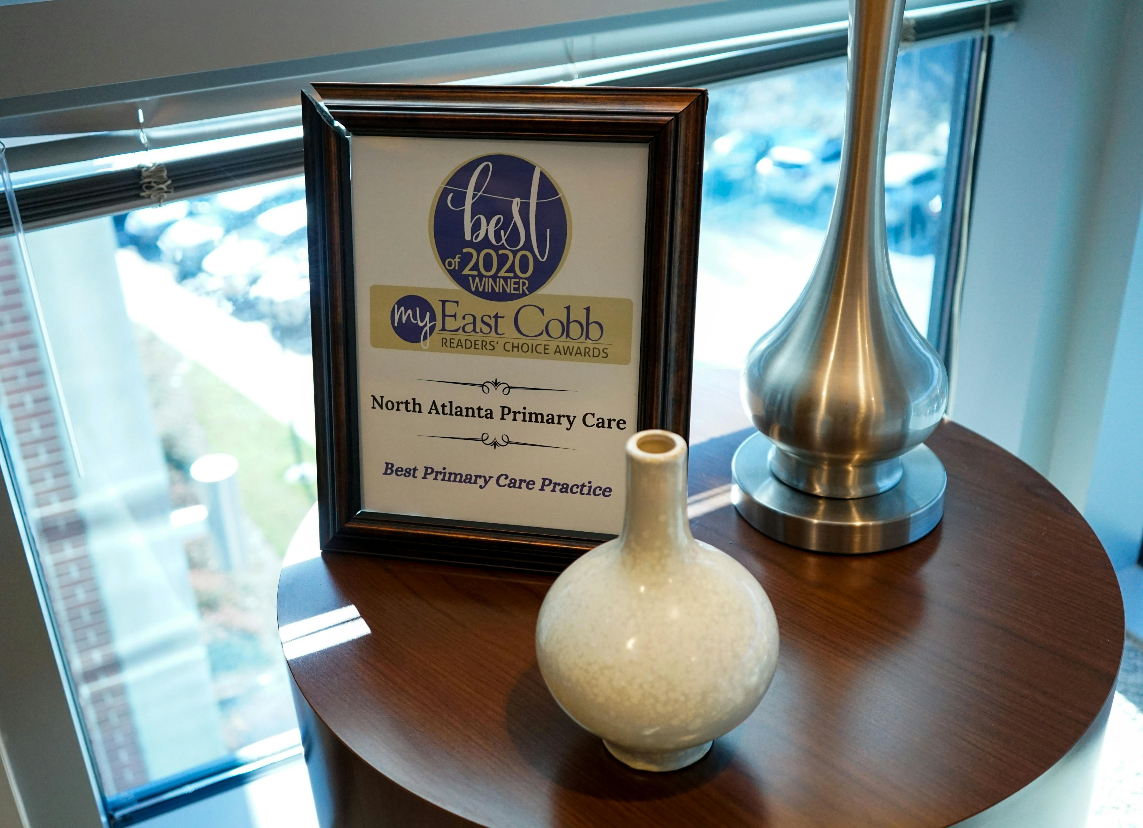 a vase is sitting on a table next to a framed sign that says north atlanta primary care best primary care practice .