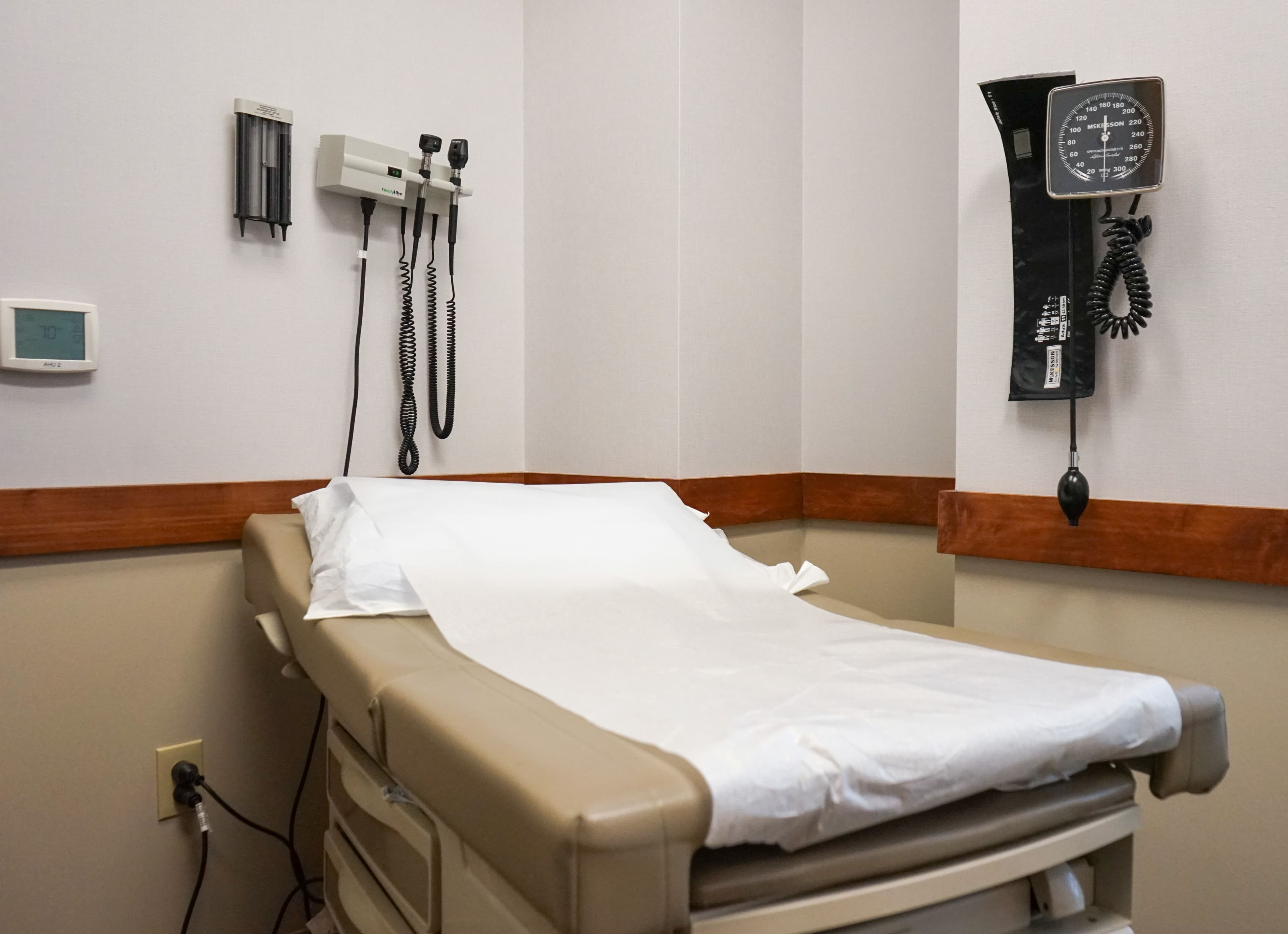 a doctor 's office with a bed and a stethoscope on the wall .