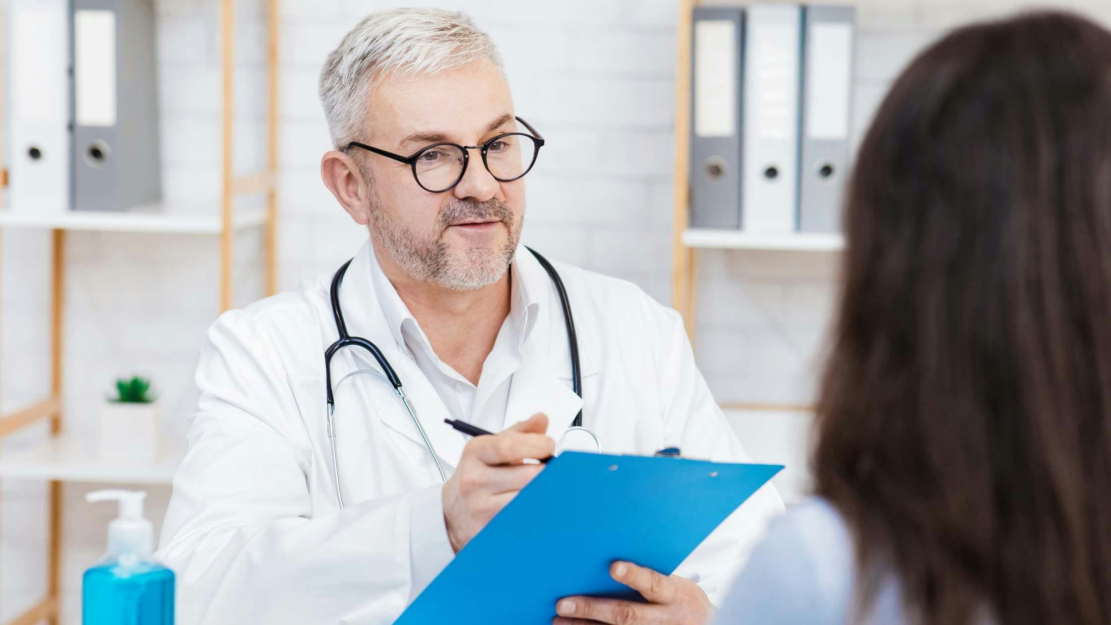 a doctor is talking to a patient while holding a clipboard .