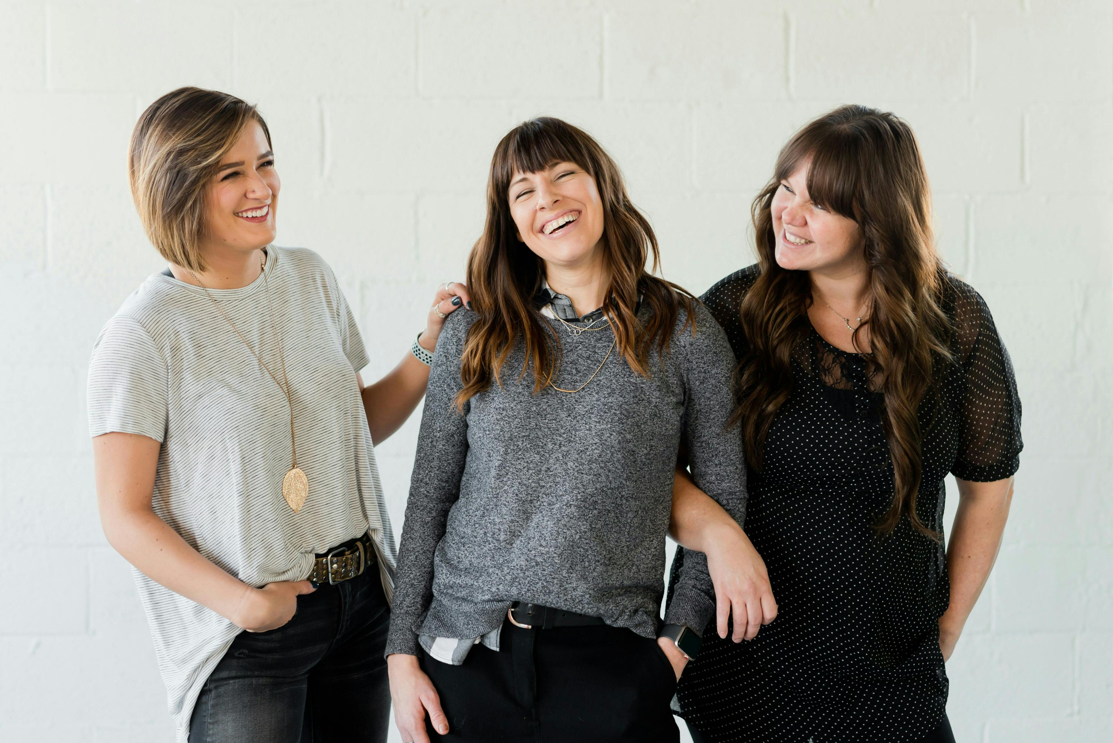 three women are standing next to each other and laughing .