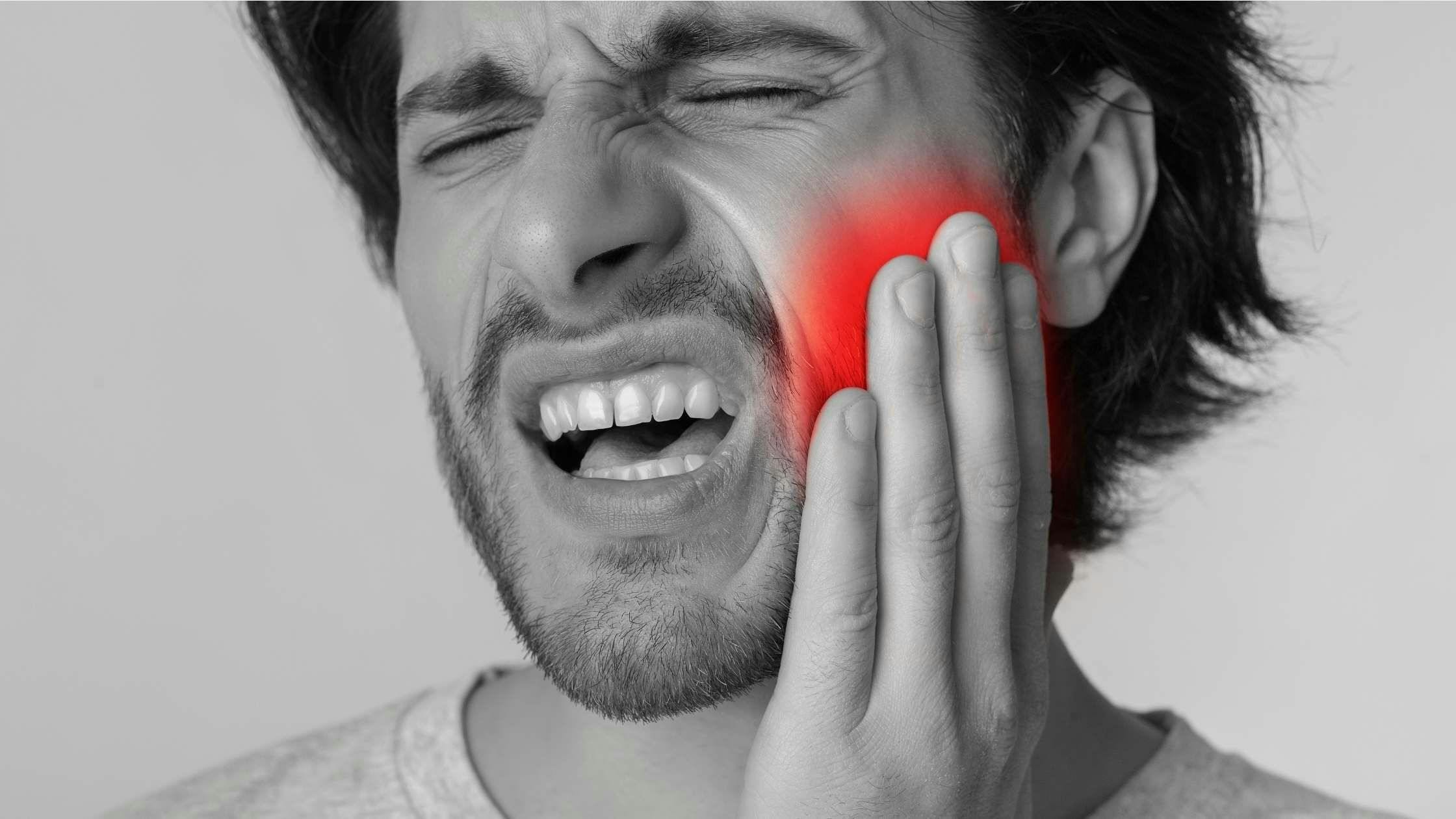 a man is holding his face in pain because of a toothache .