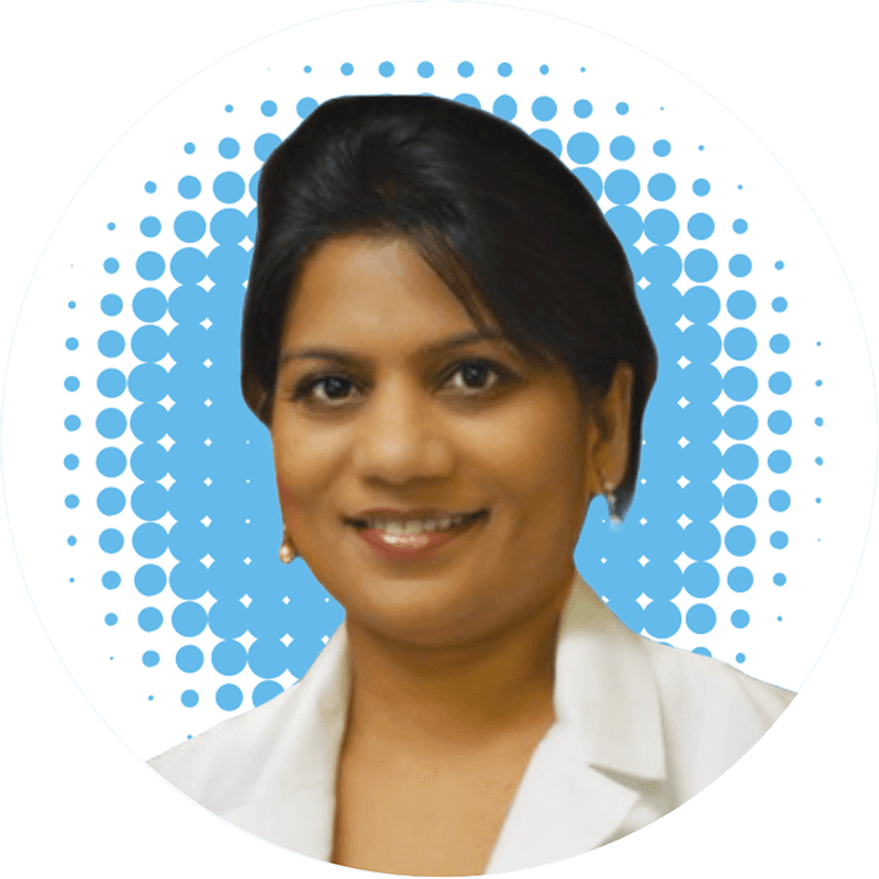 Dr. Vijitha Prasad, MD, in a white coat is smiling in front of a blue polka dot background