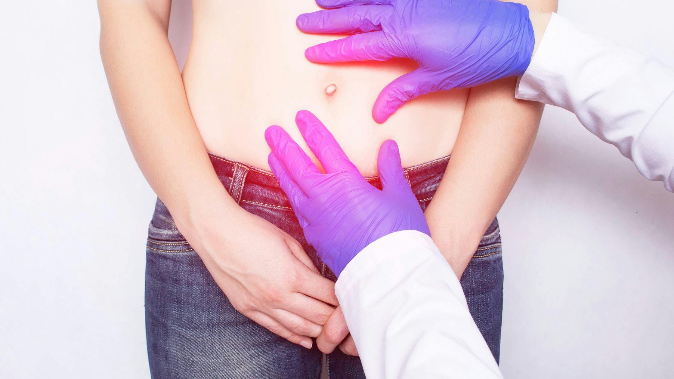 a doctor is examining a woman 's stomach with purple gloves .