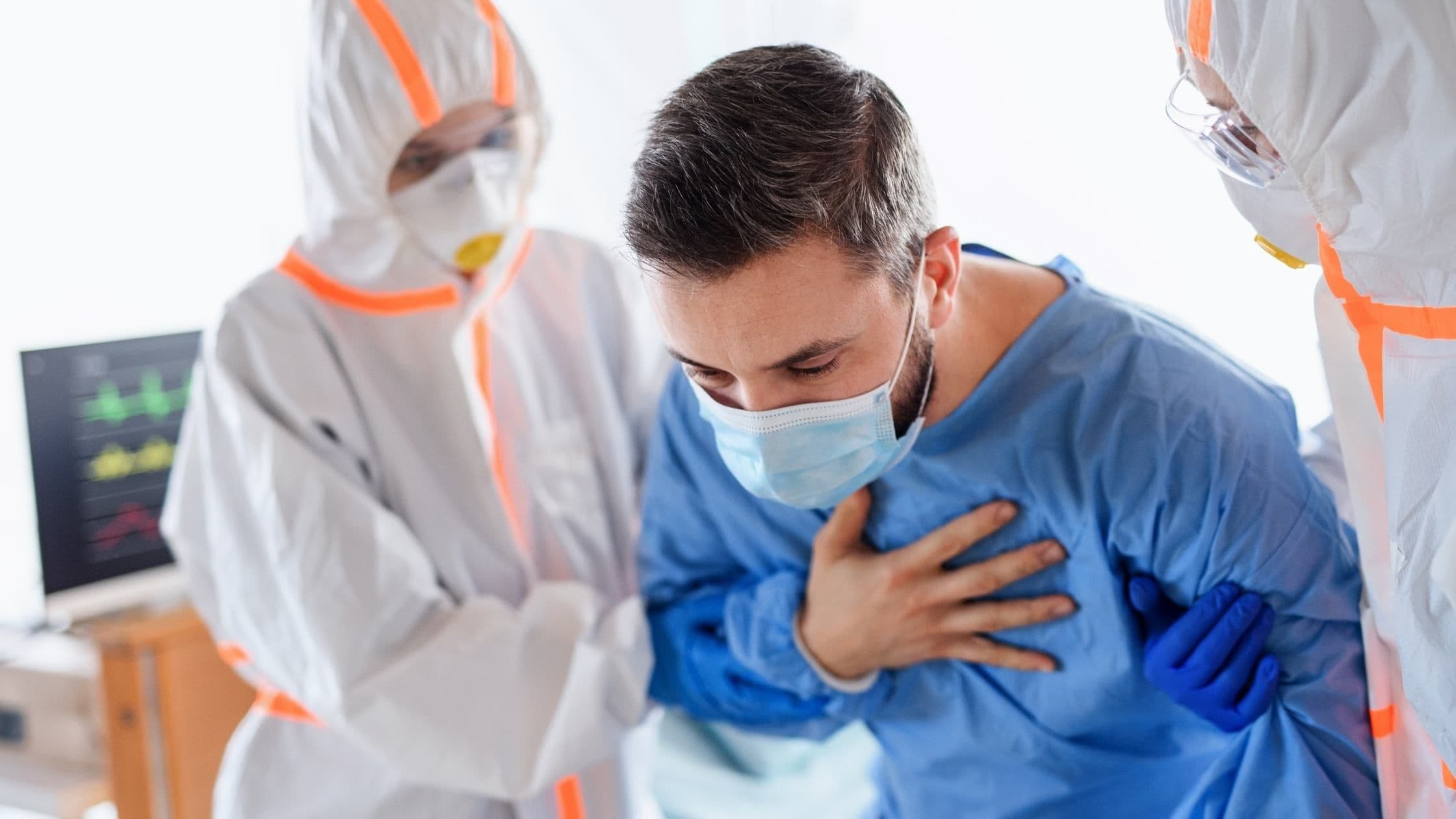 a man wearing a mask is having a heart attack in a hospital room .