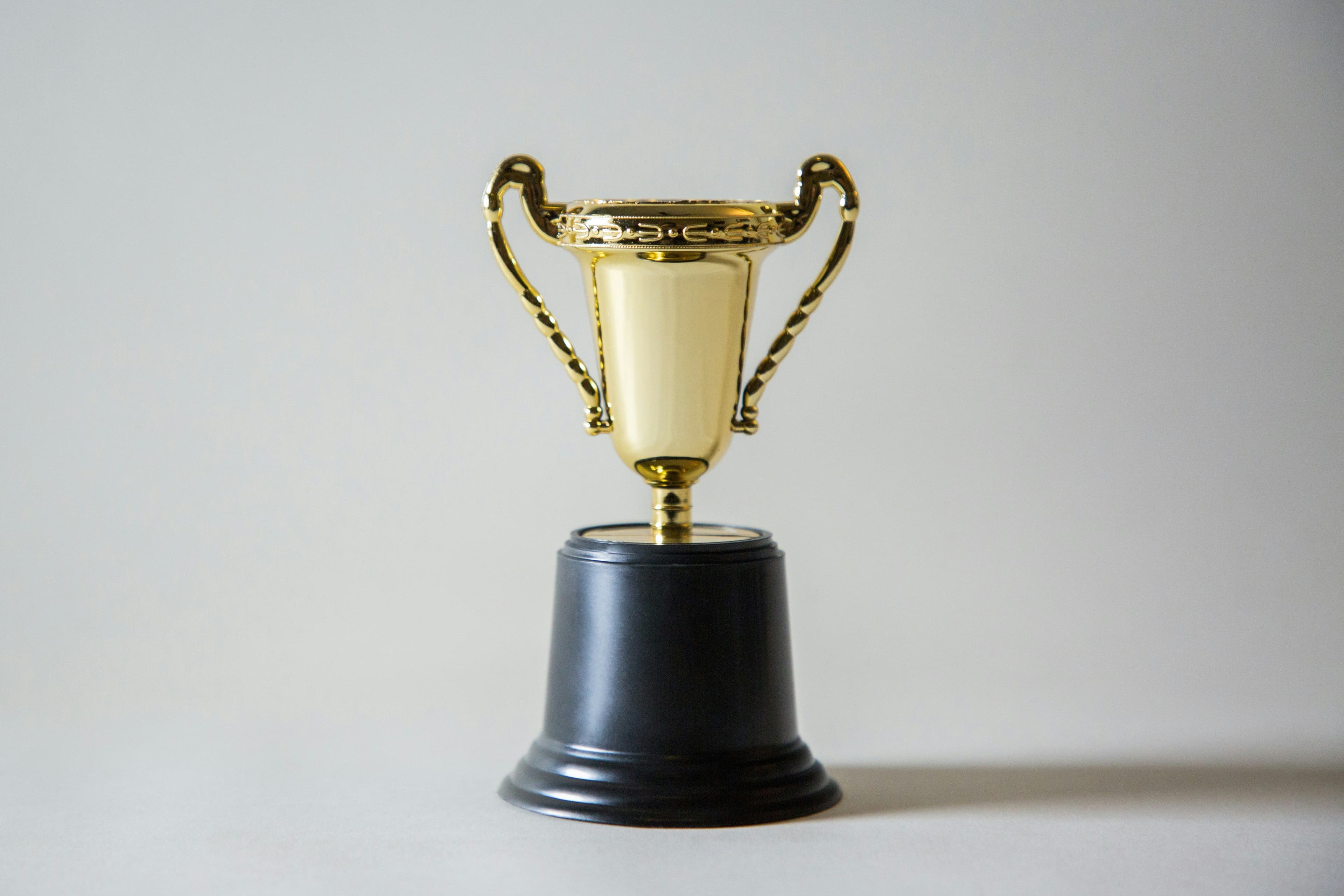 a gold trophy on a black base on a white background .