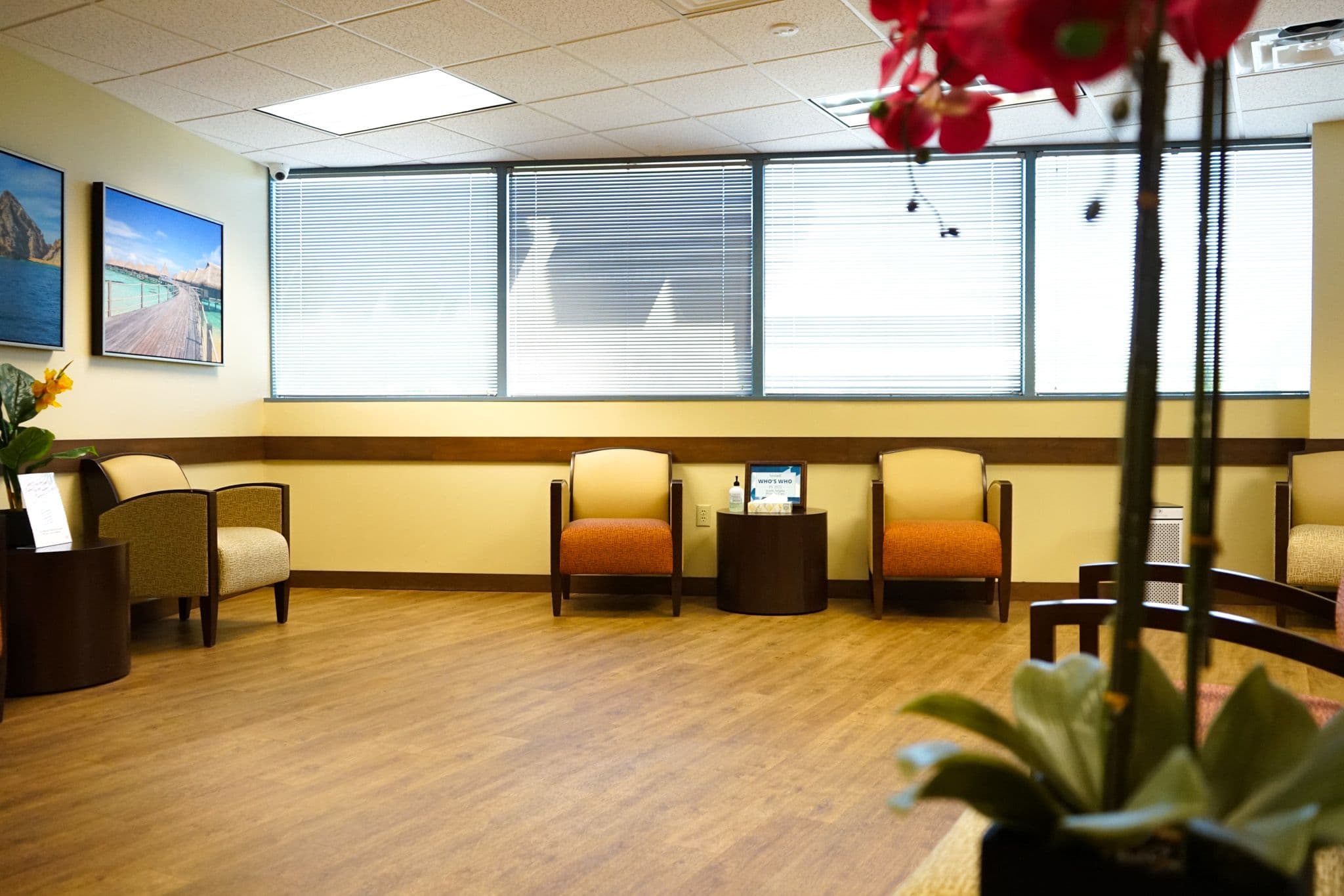 a waiting room with chairs , tables and a vase of flowers .