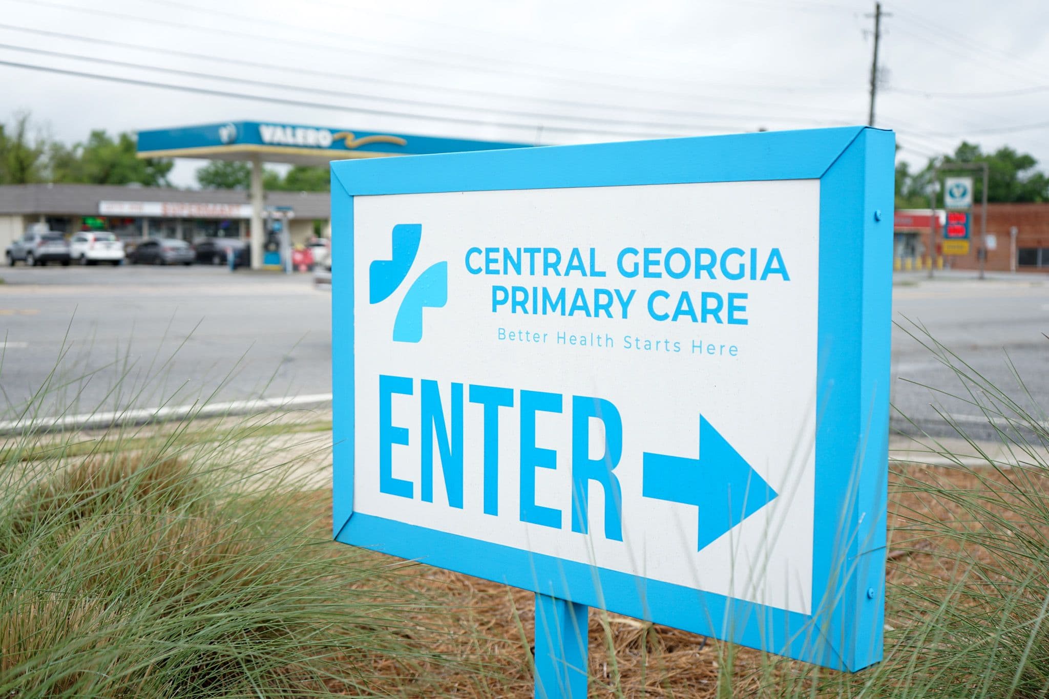 a blue and white sign for central georgia primary care with an arrow pointing to the right .