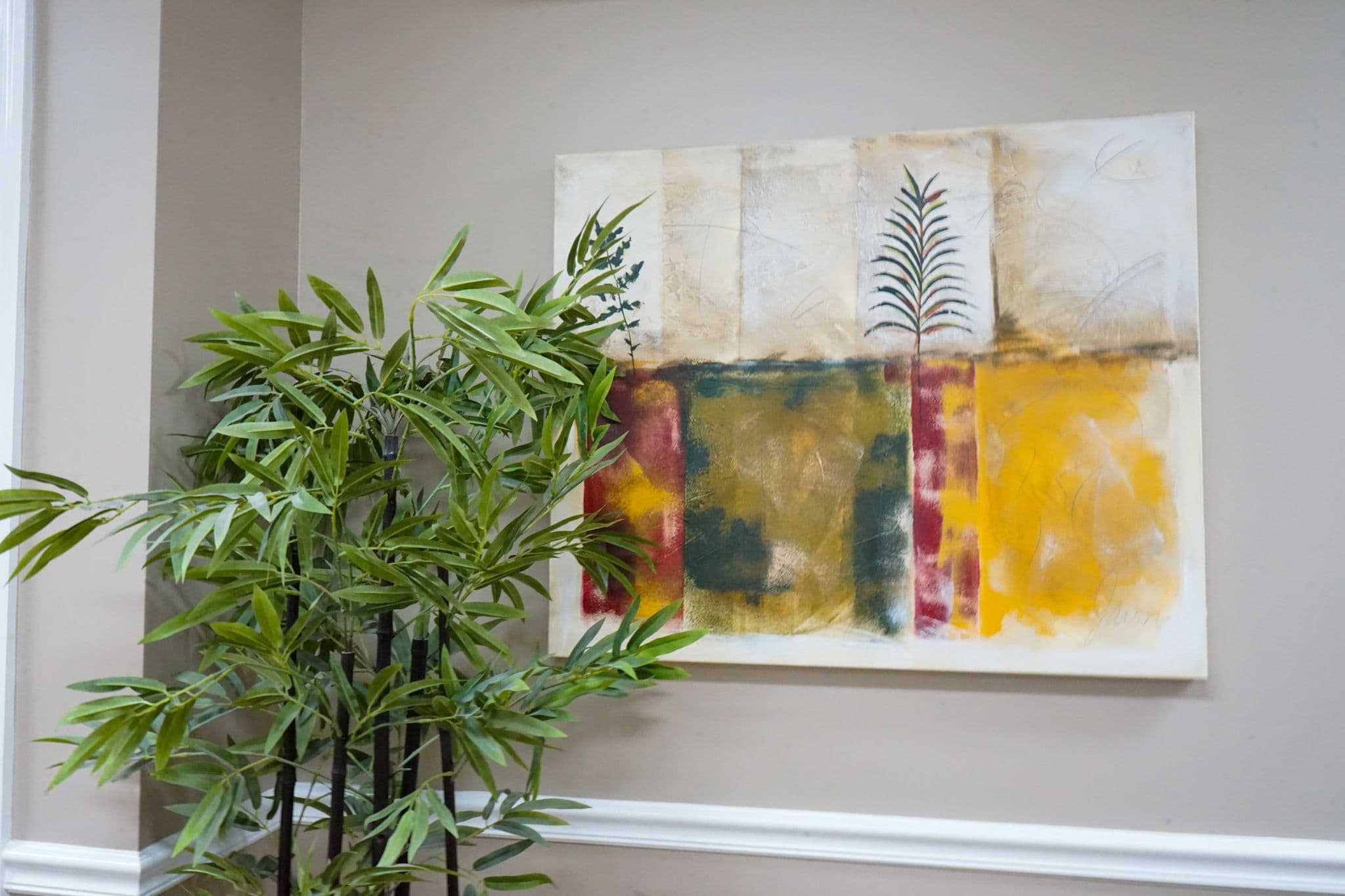 a painting is hanging on a wall next to a plant  at South Georgia Internal Medicine at Swainsboro .