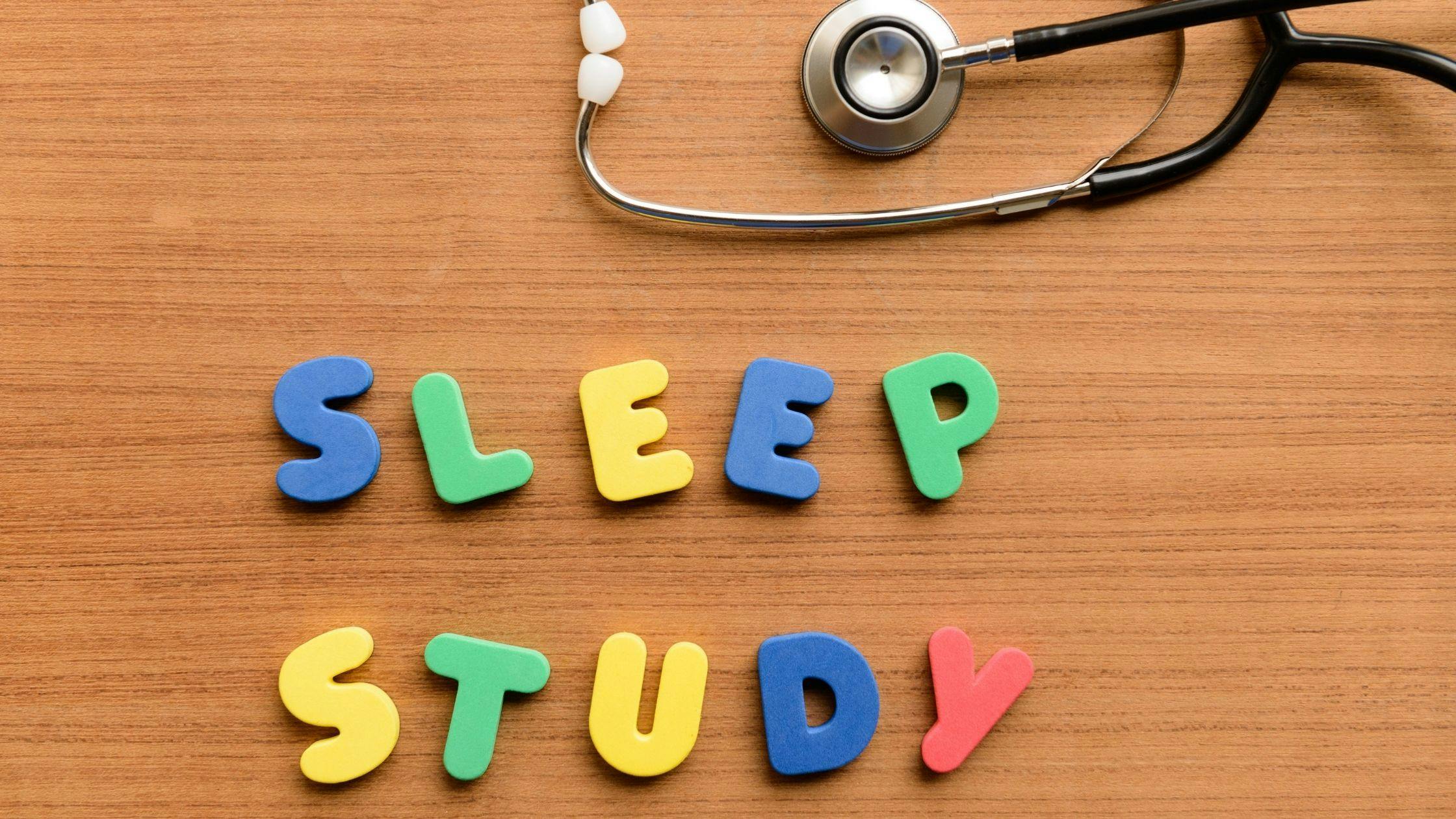 the word sleep study is made of colorful letters and a stethoscope on a wooden table .