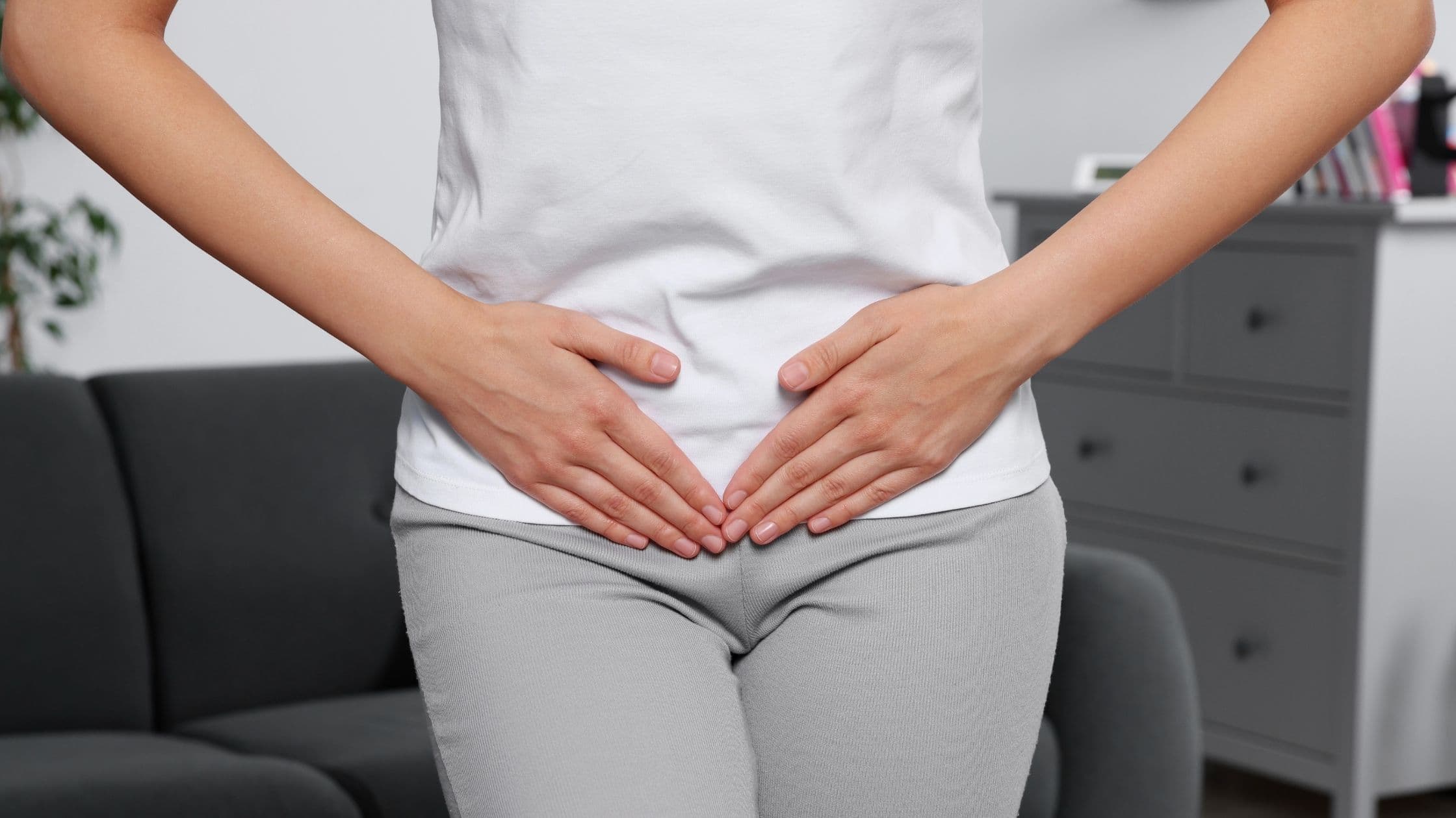 a woman is holding her stomach in pain in a living room .