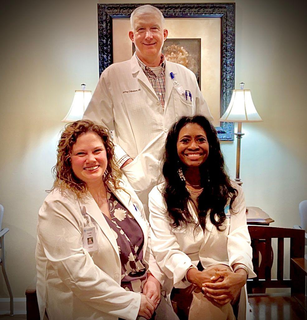 a group of doctors are posing for a picture in front of a framed picture .