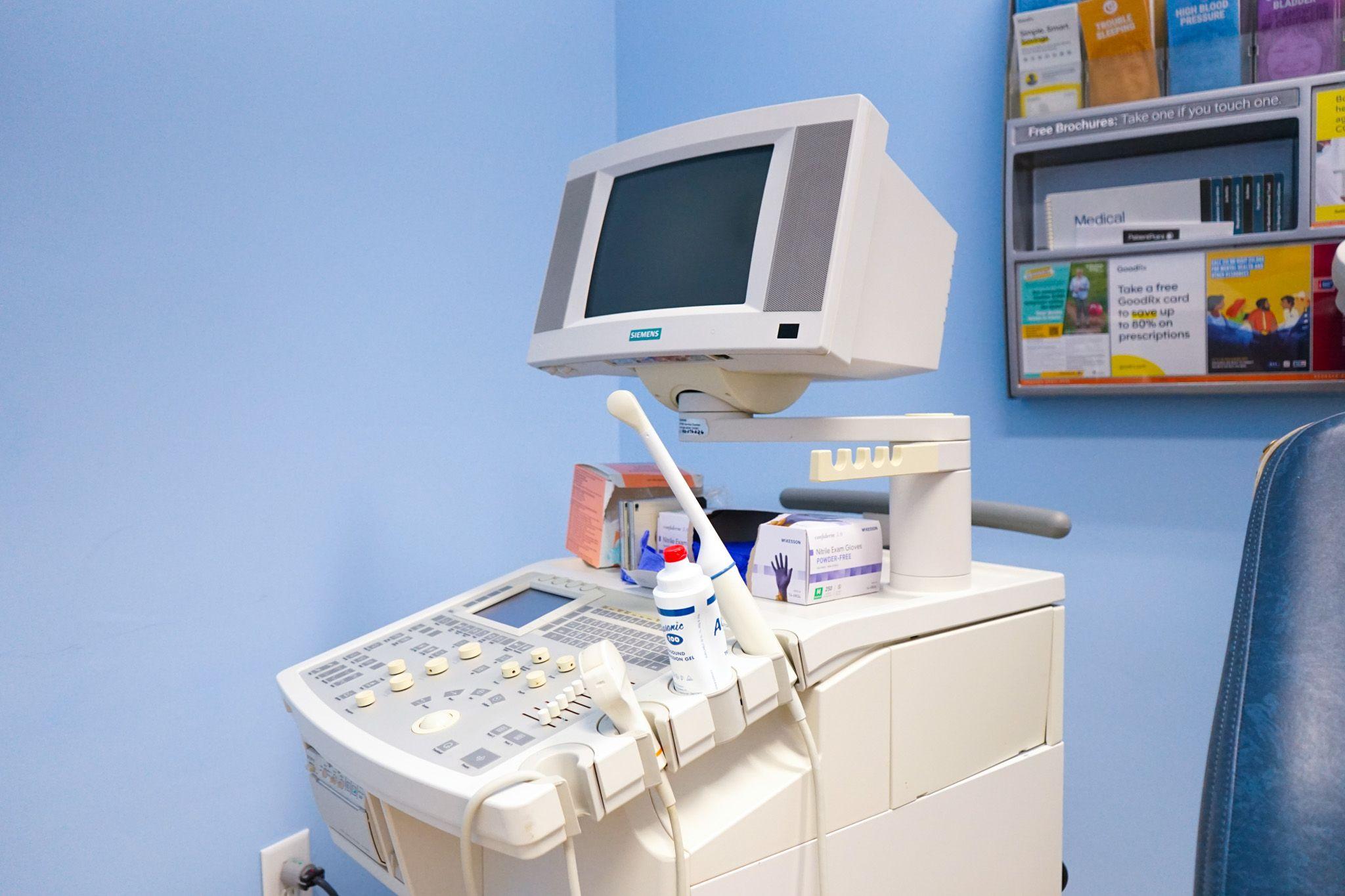 an ultrasound machine is sitting in a blue room next to a chair .