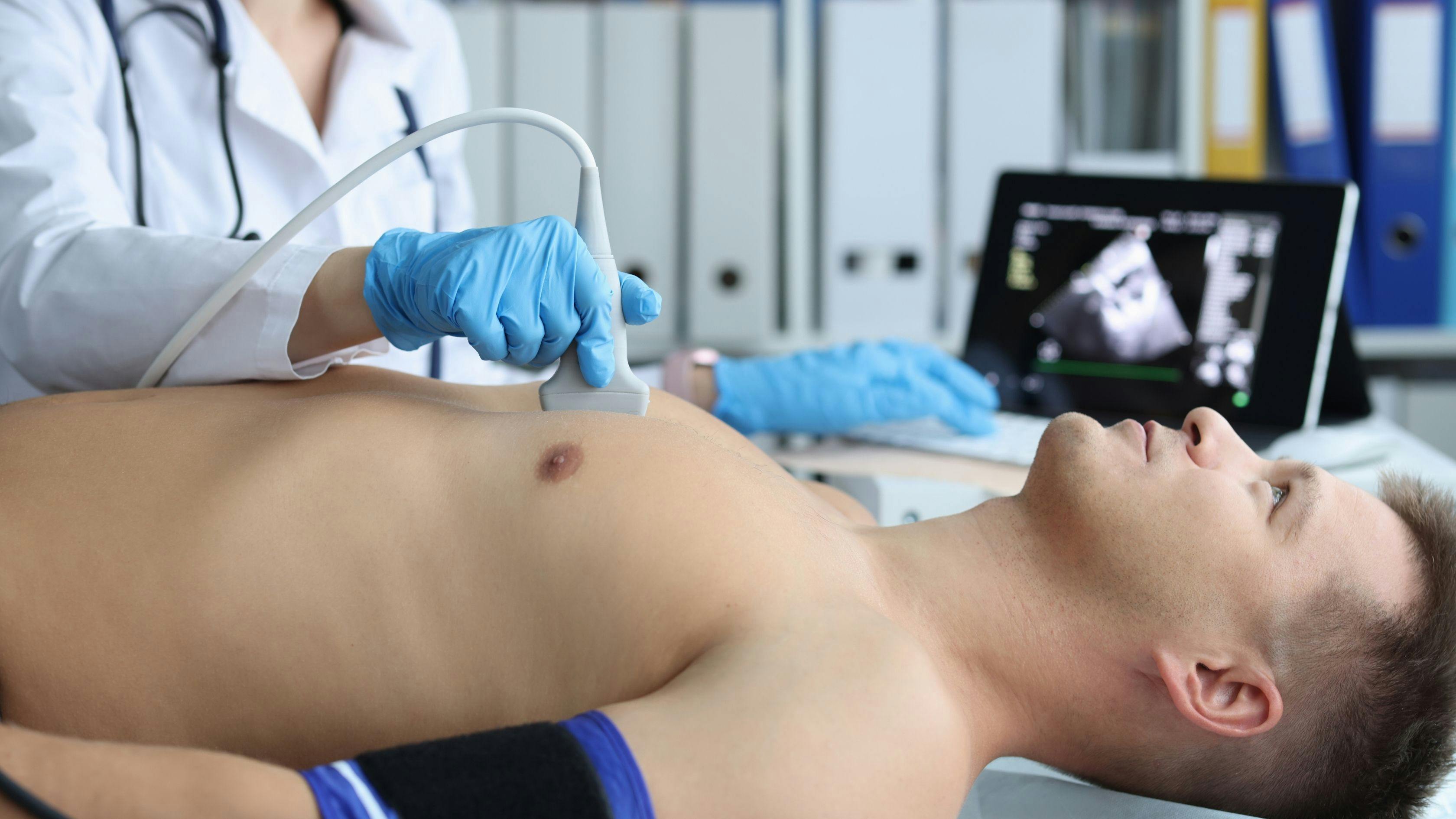 a man is getting an ultrasound of his chest by a doctor .