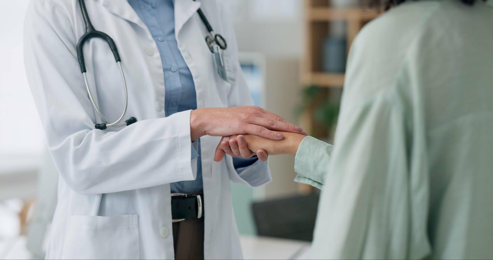 a doctor is holding the hand of a doctor in a hospital .