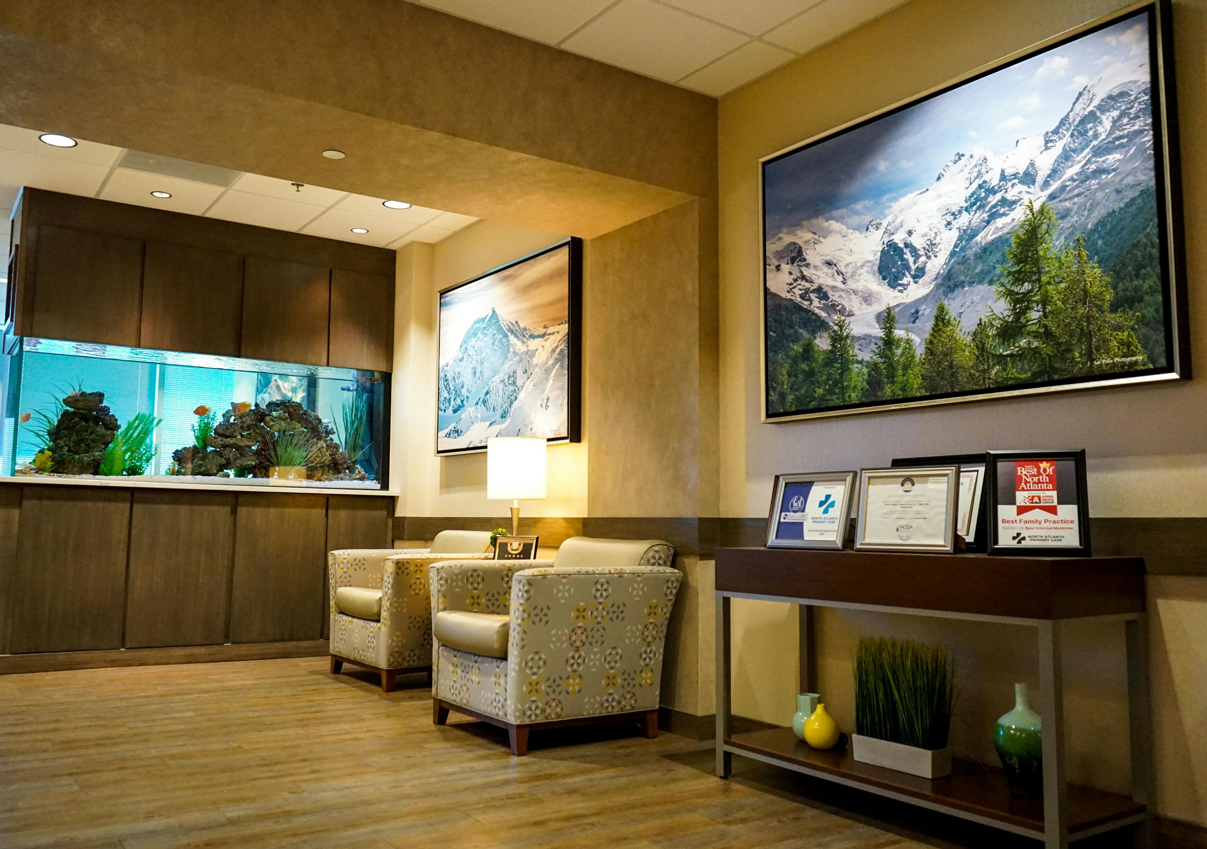 a waiting room with chairs , a fish tank , and a painting on the wall .