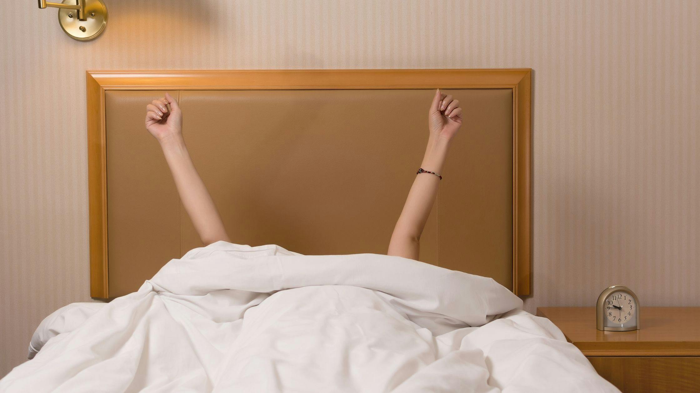 a woman is laying in bed with her arms outstretched .
