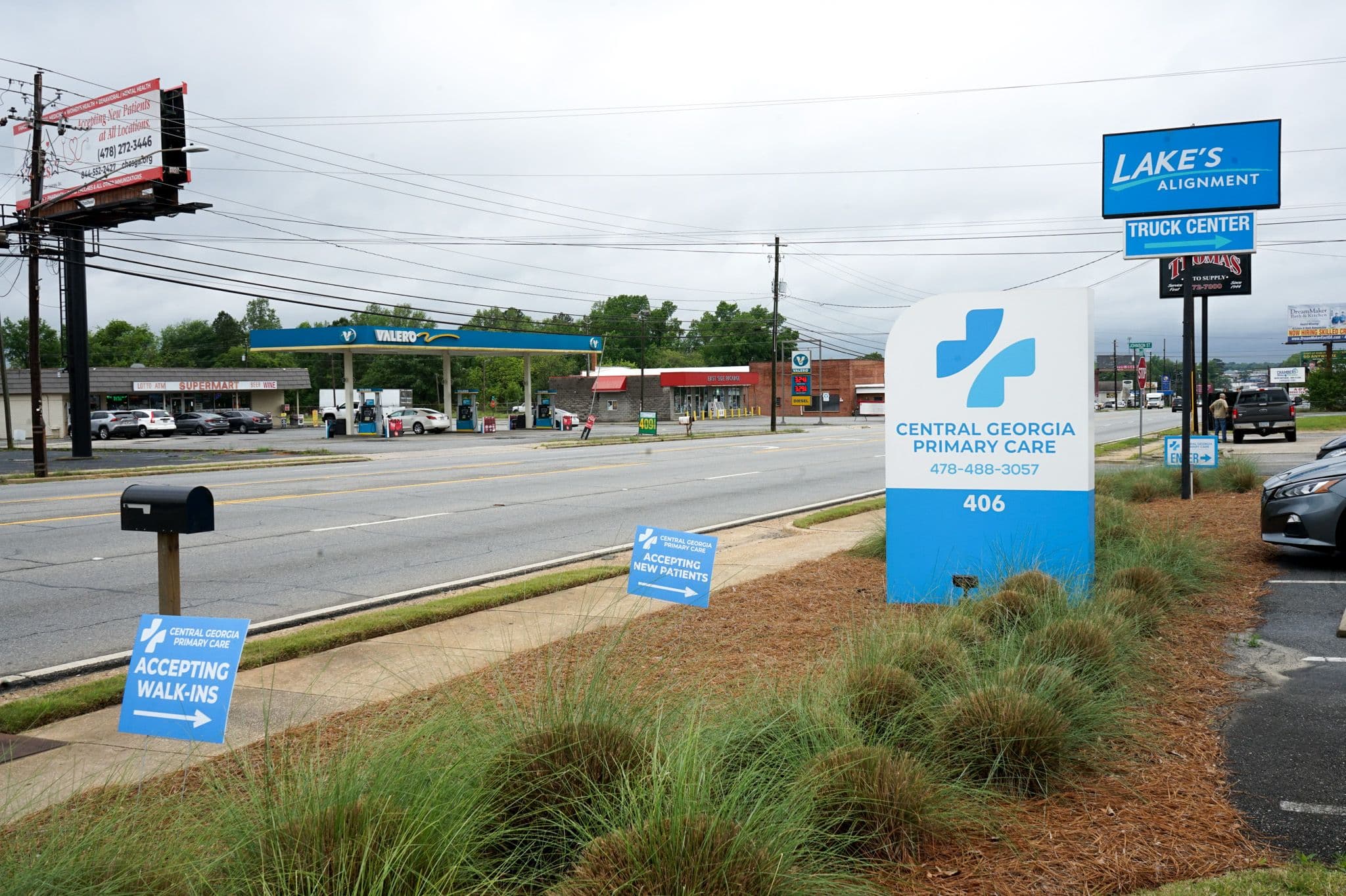 a sign for central georgia pain care is sitting on the side of a road next to a gas station .