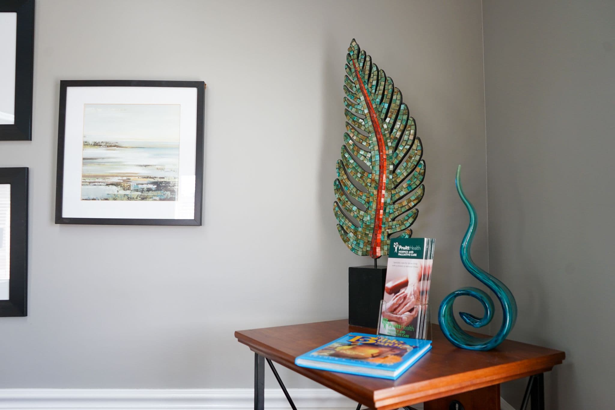 a table with a leaf sculpture , a book , and a statue on it at South Georgia Internal Medicine at Swainsboro .