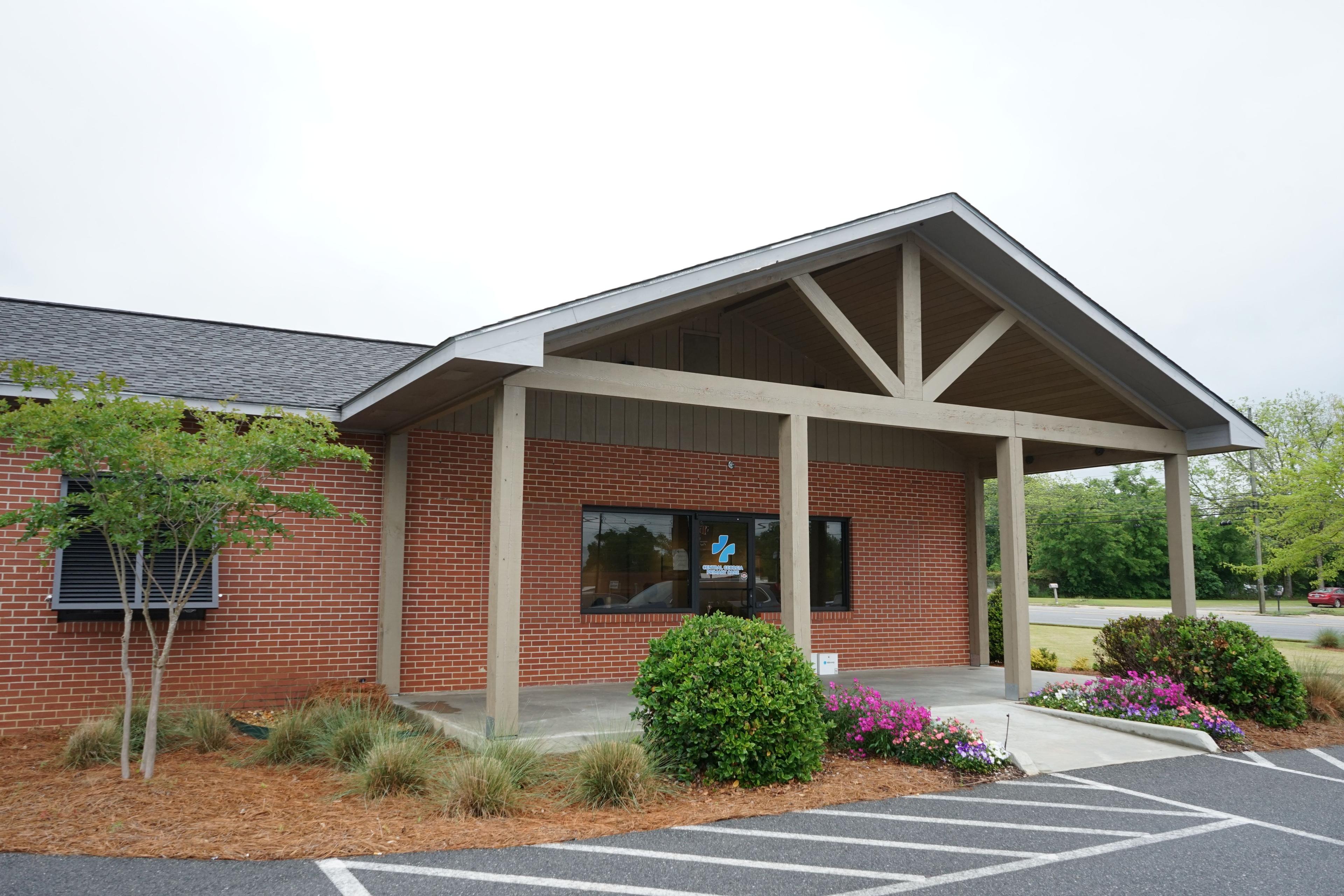 a brick building with a porch and a parking lot in front of it .