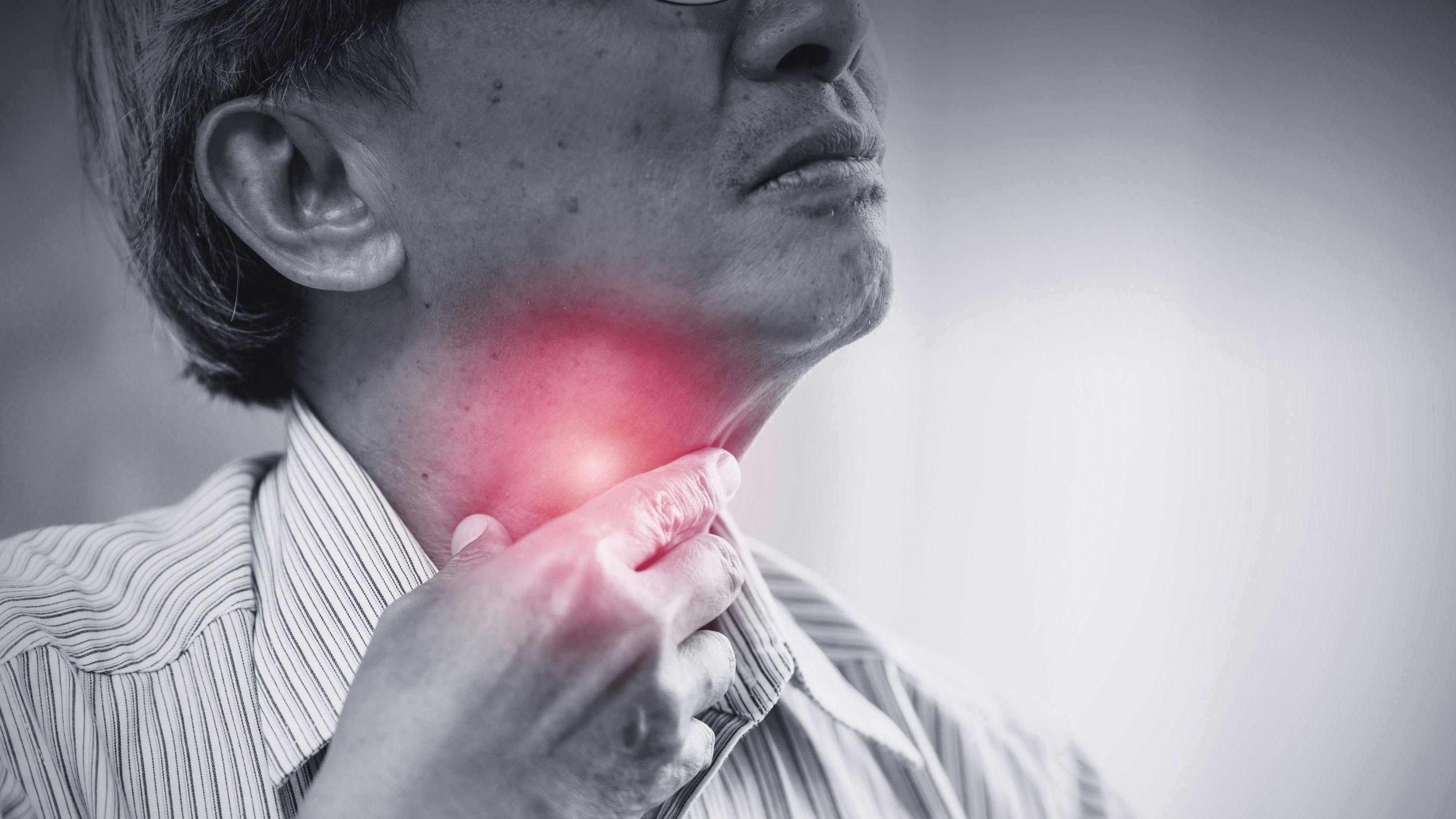 a man is holding his neck in pain because he has a sore throat .