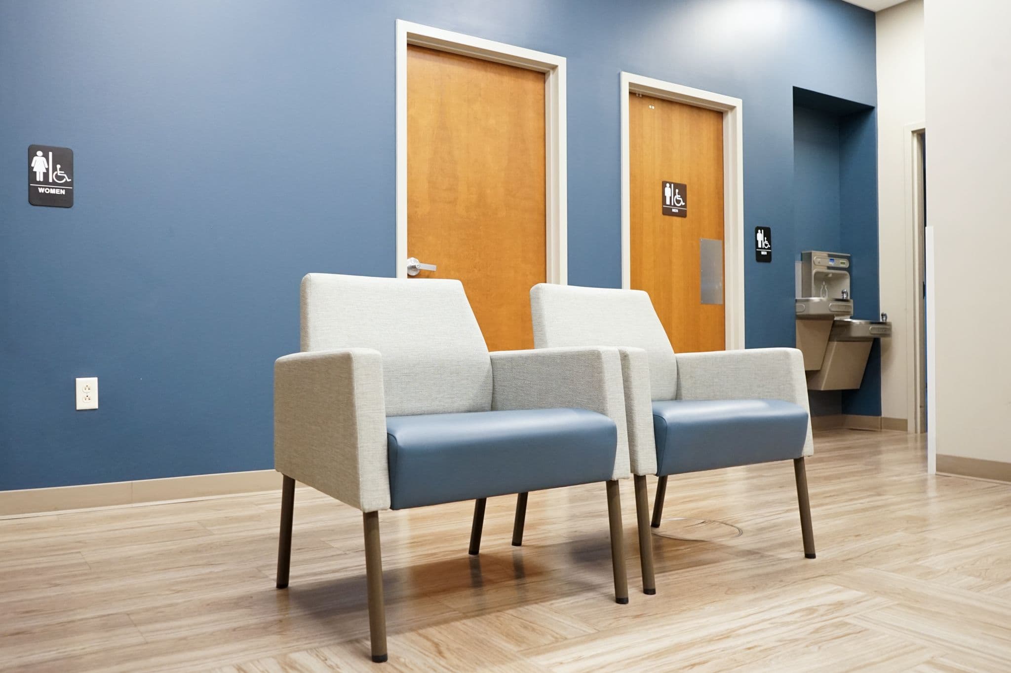 two chairs are sitting in Restore Health & Wellness waiting room next to two doors .